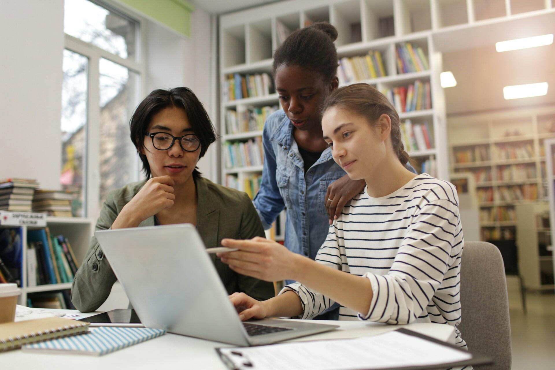 three students looking at a computer together as part of a study group