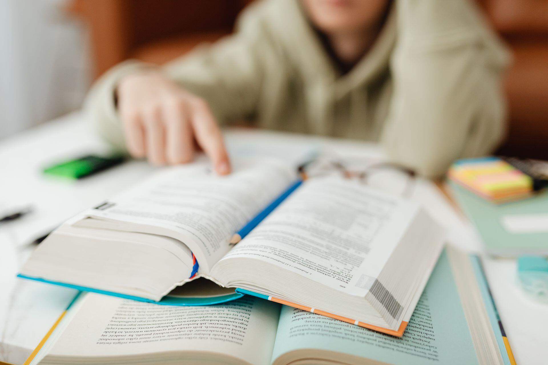 student with many textbooks reading and highlighting important information