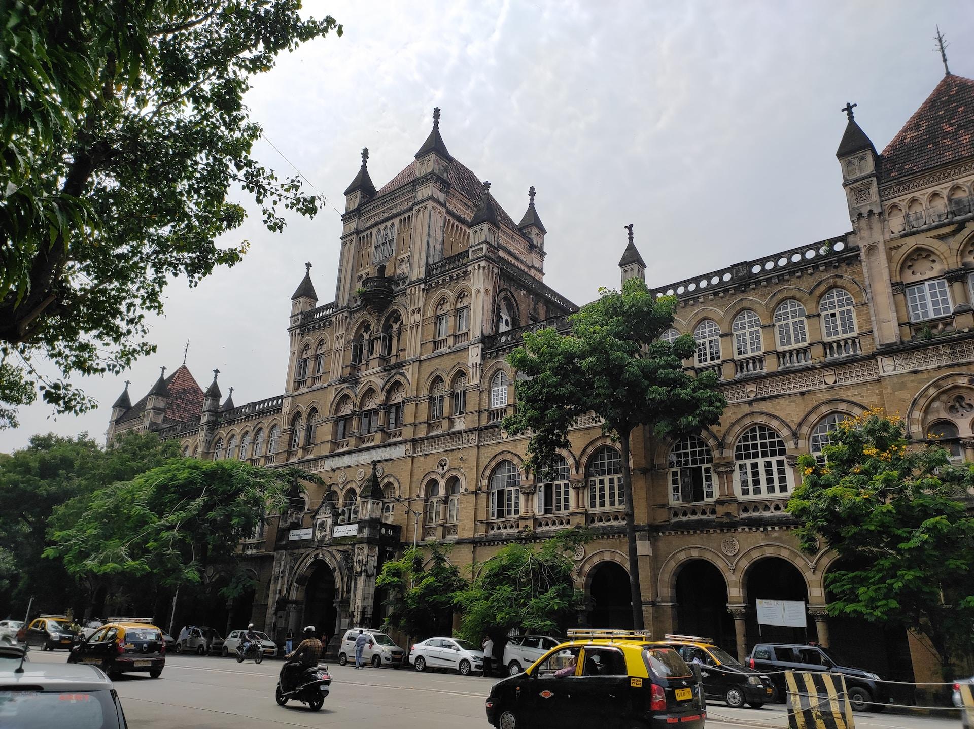 A large college building in Mumbai built in Victorian style, set against a grey, leaden sky.