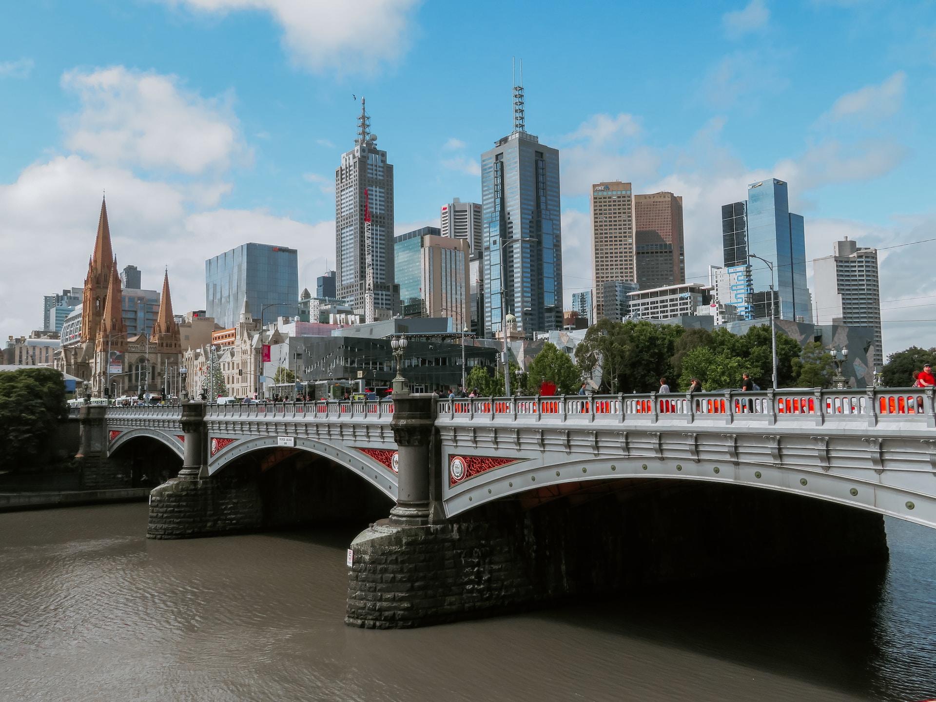 A panoramic view of the Melbourne skyline under a blue sky with fleecy white clouds.