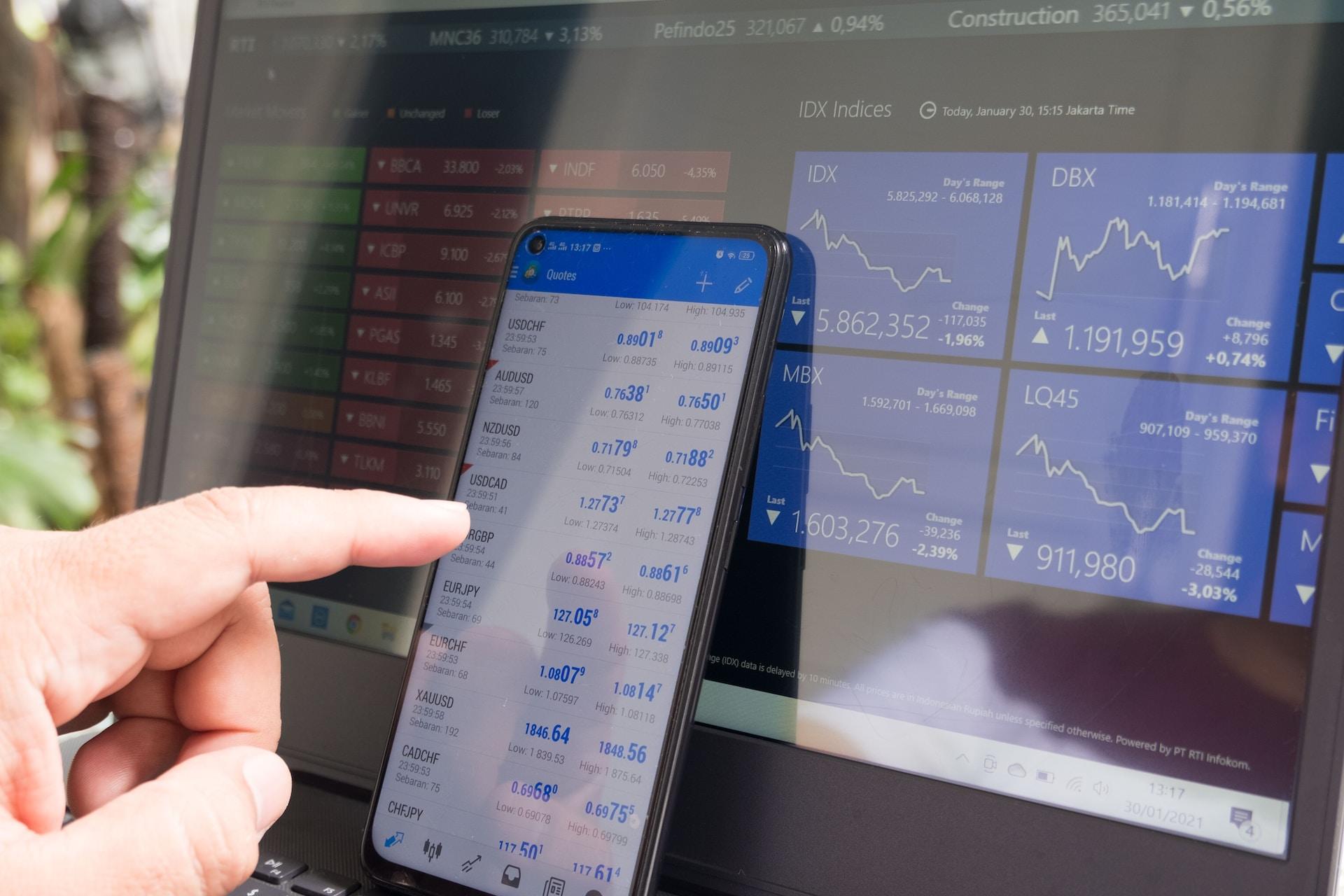 A smartphone and laptop being used to trade stocks.