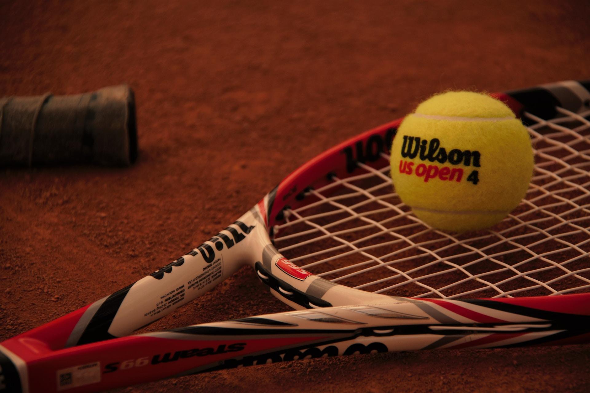 A Wilson tennis ball on a racket.