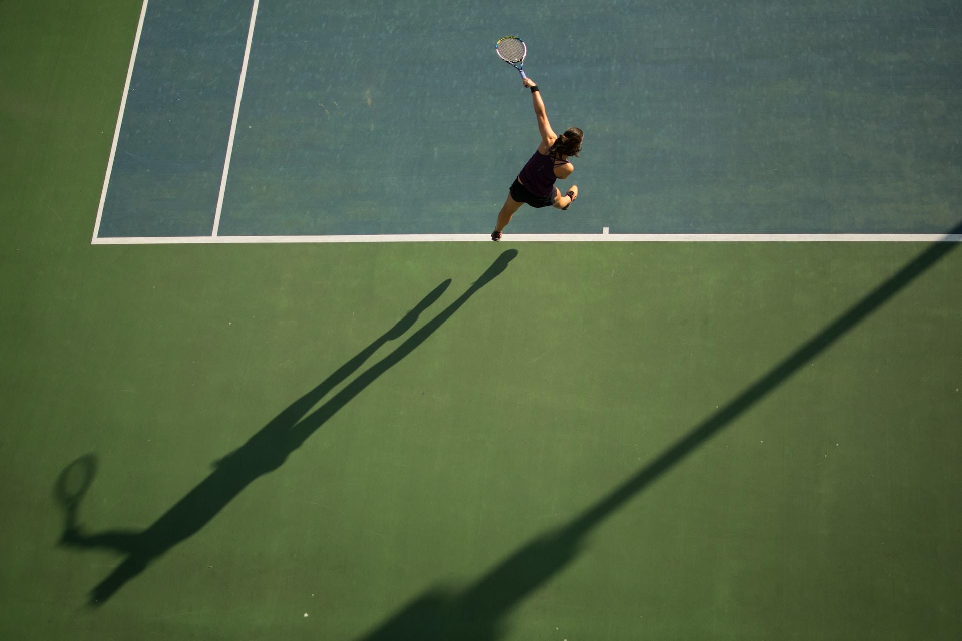 A tennis player serving on a hard court.
