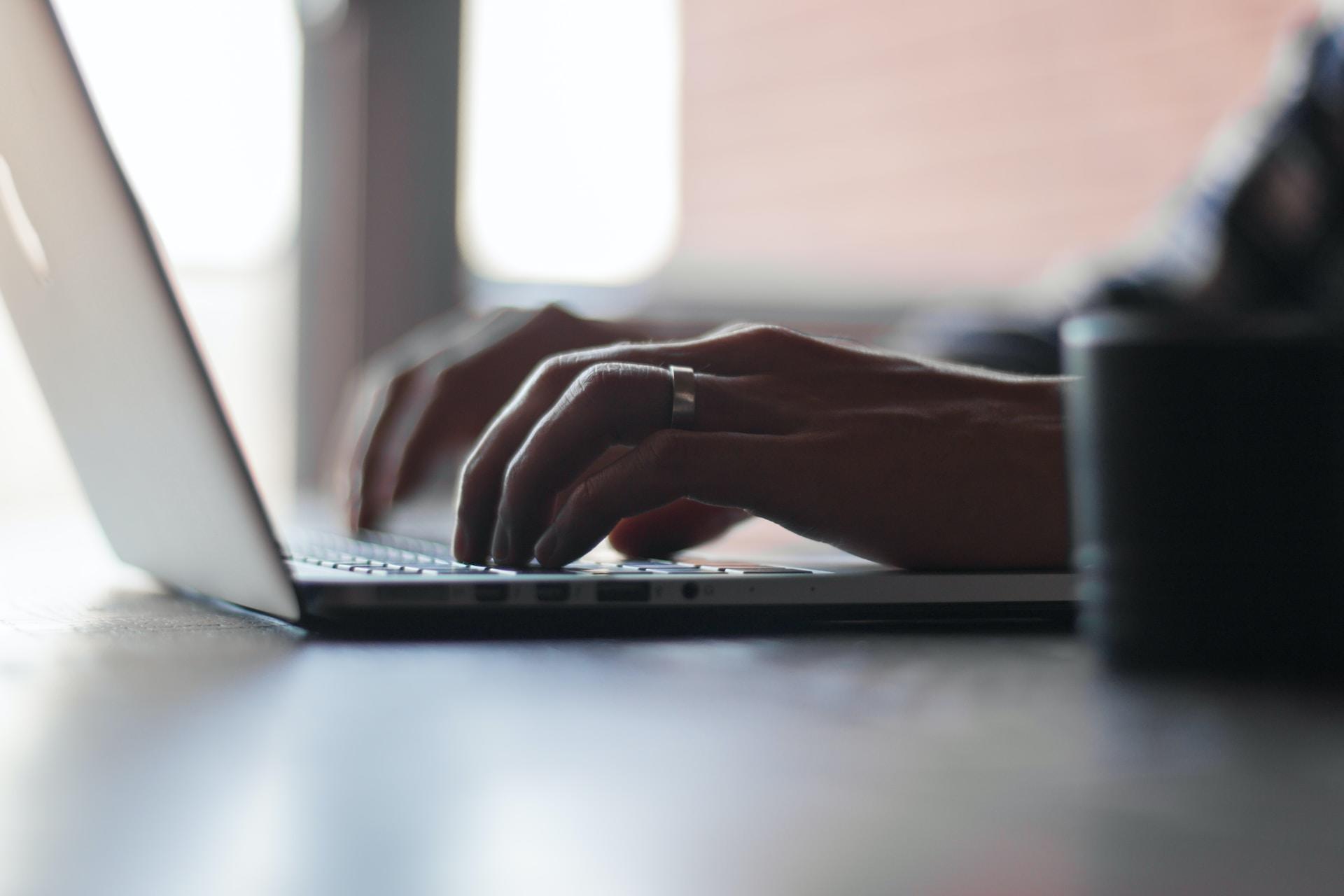 A closeup of hands typing on a laptop.