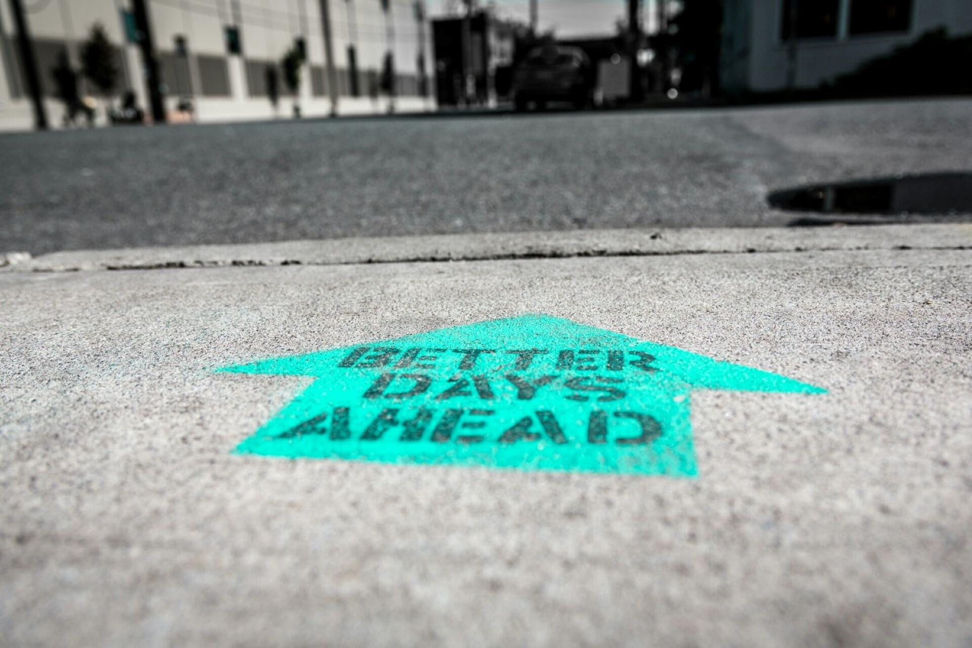 Green arrow painted on pavement with the words “Better Days Ahead”