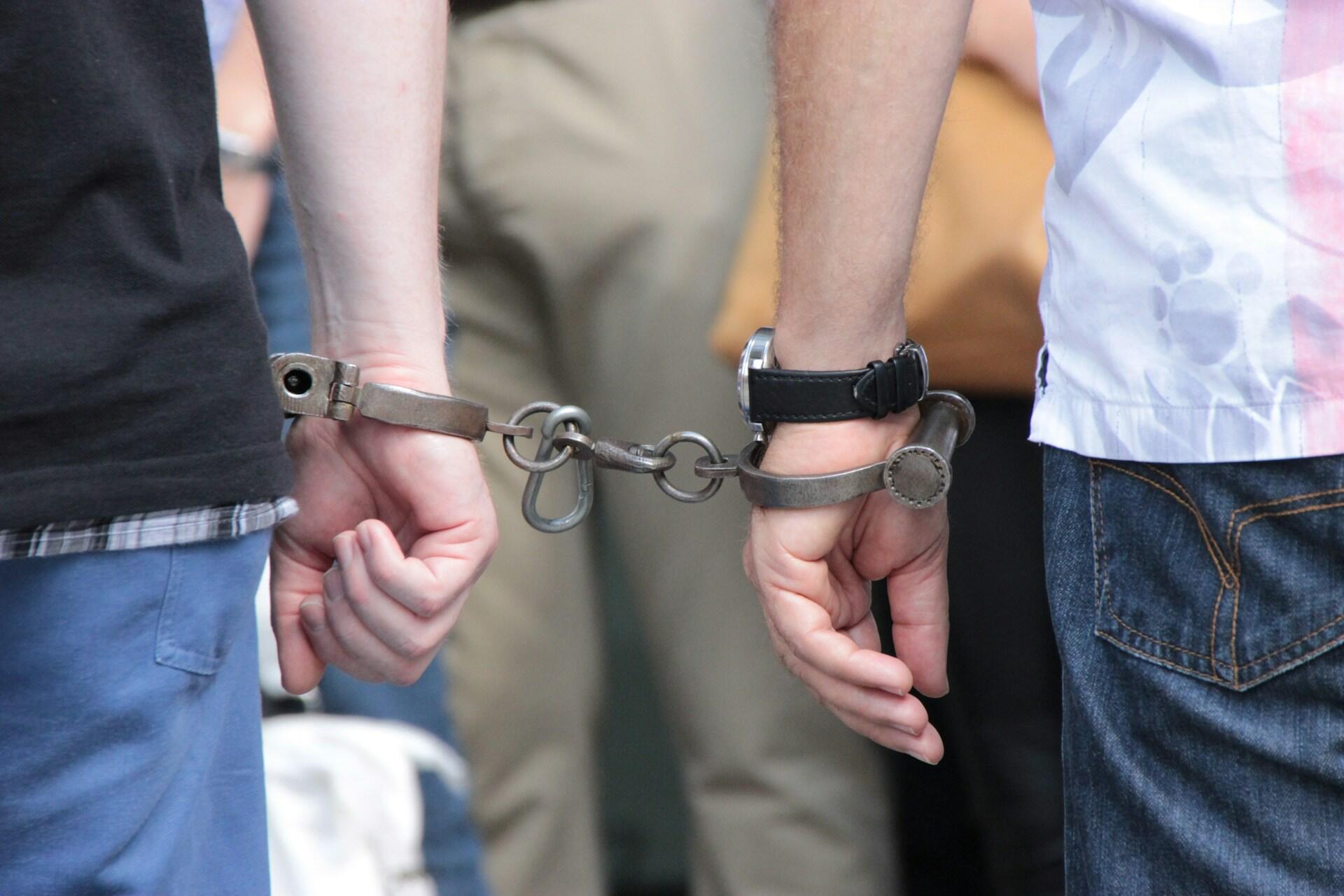 Two people standing side by side with their hands cuffed together