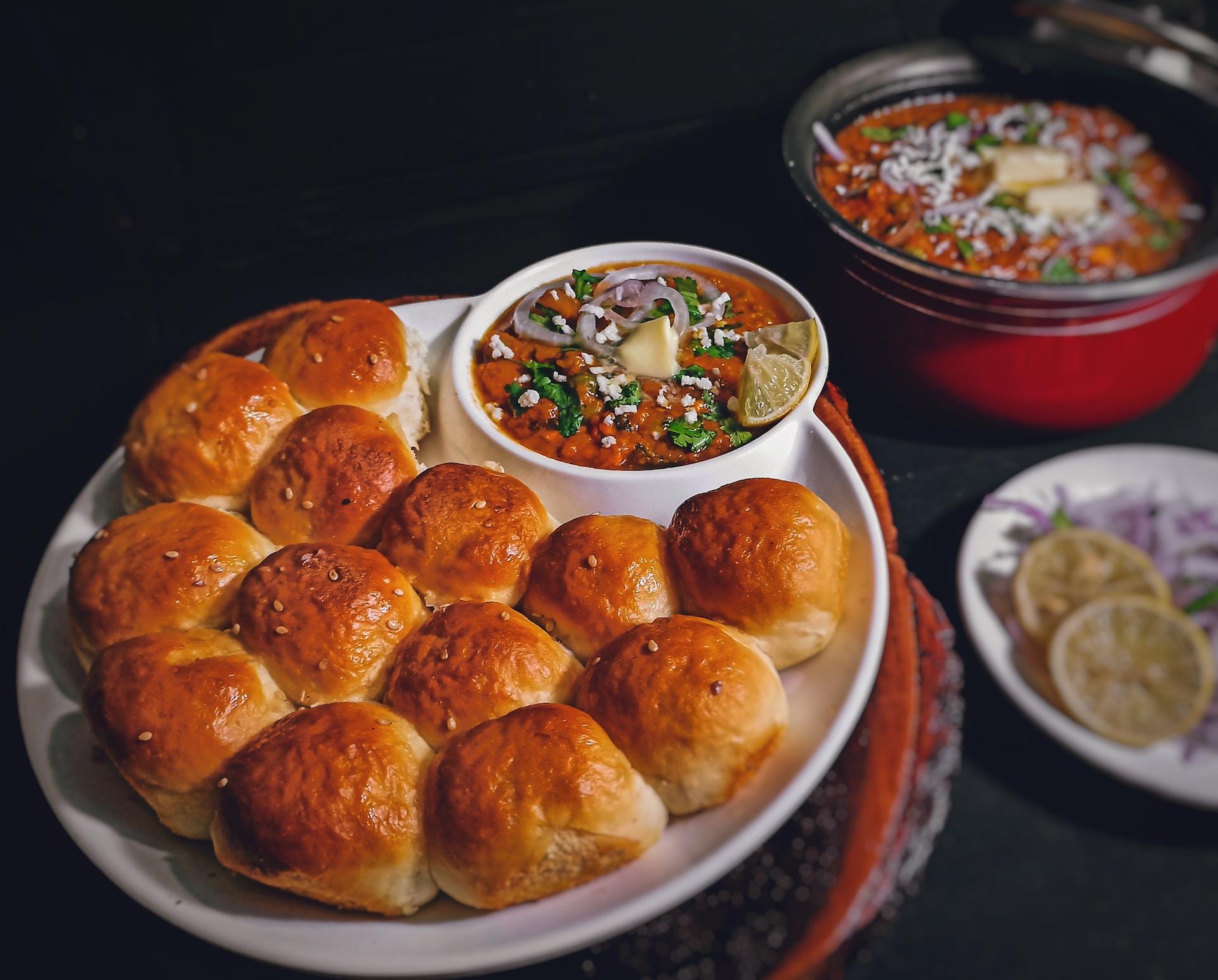 Brown rolls and a bowl of lentils on a round white plate.