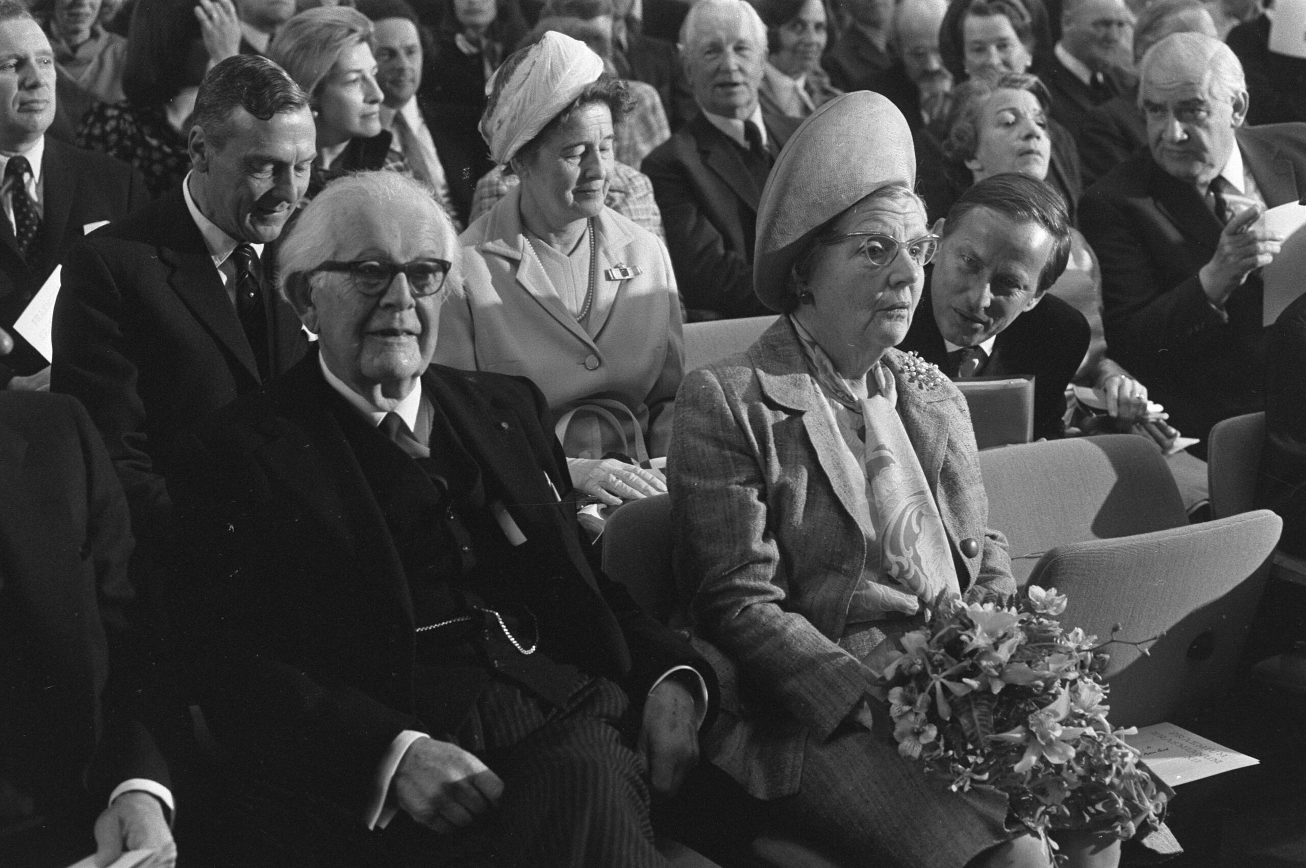 Black and white photograph of people (including Jean Piaget) seated at a formal public event or lecture