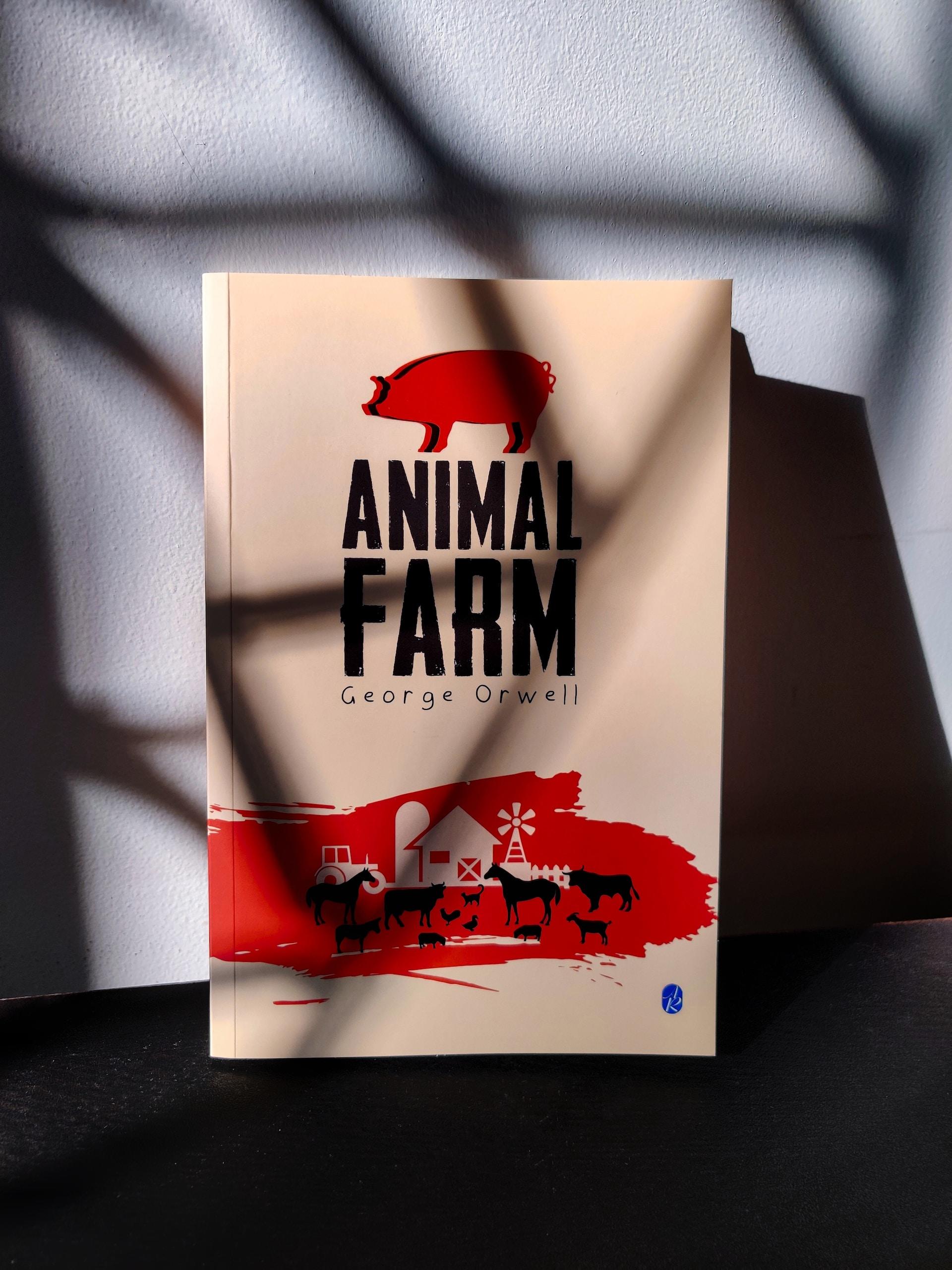 The book Animal Farm, a pale yellow cover with a red pig at the top and a barnyard scene outlined against a red background at the bottom, with the animals and the title printed in black ink. 