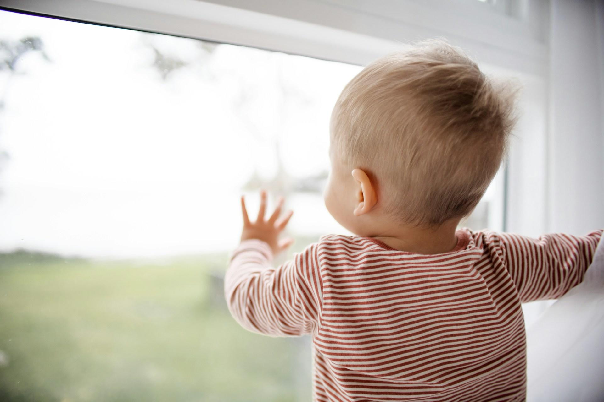 A baby looking out of a window.