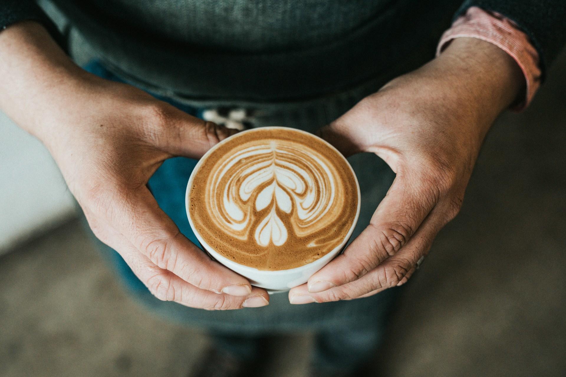 A barista holding a coffee.