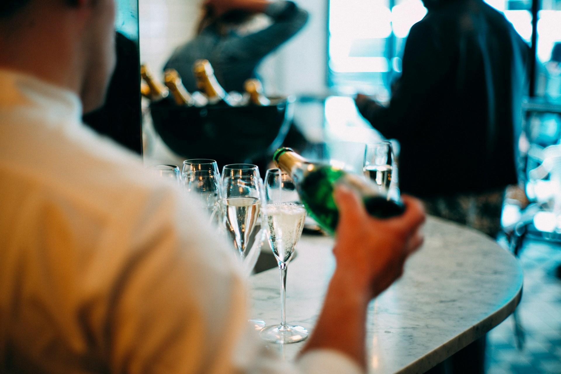 A person pouring champagne in a hospitality role.
