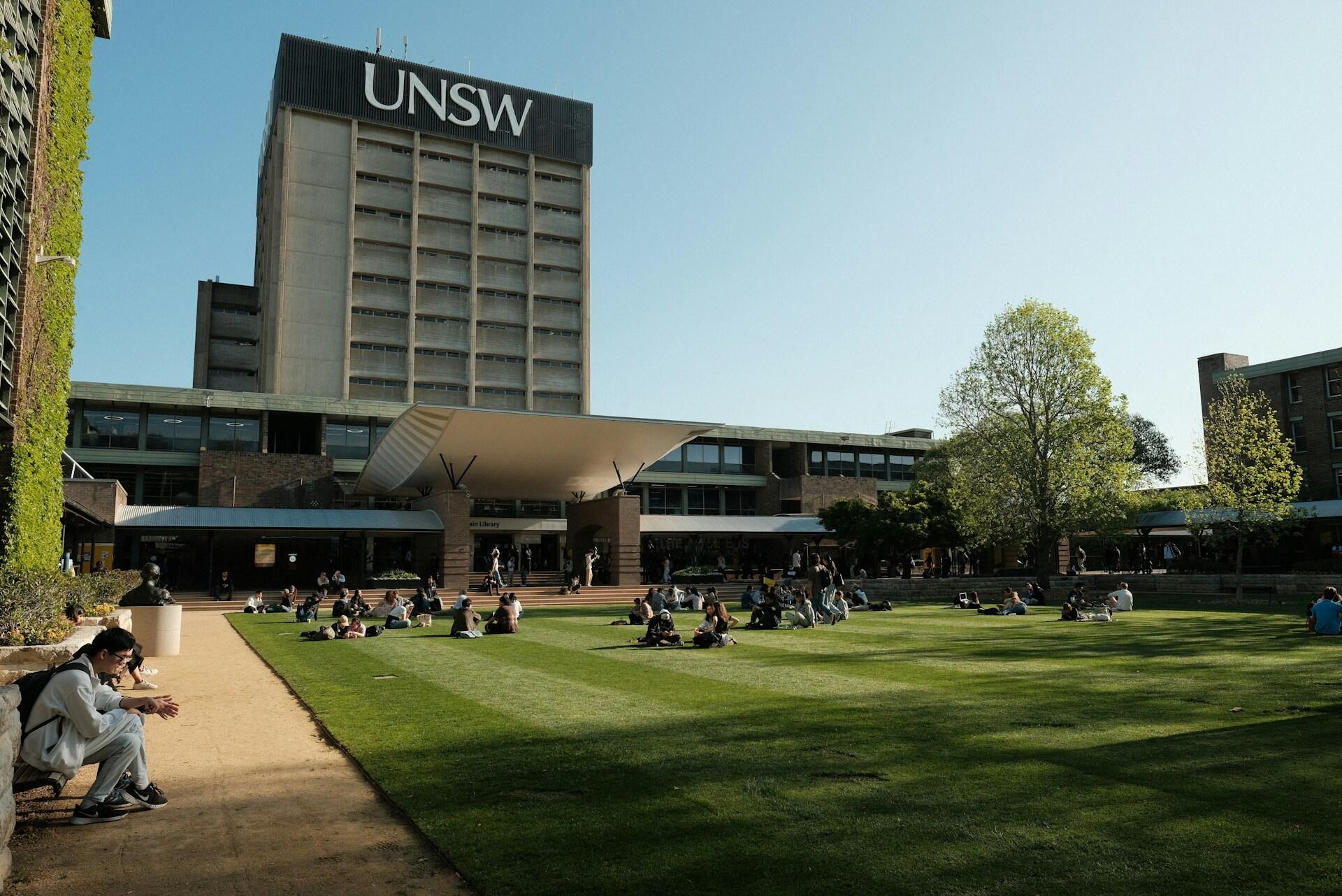 A large building behind an open green space on a sunny day.