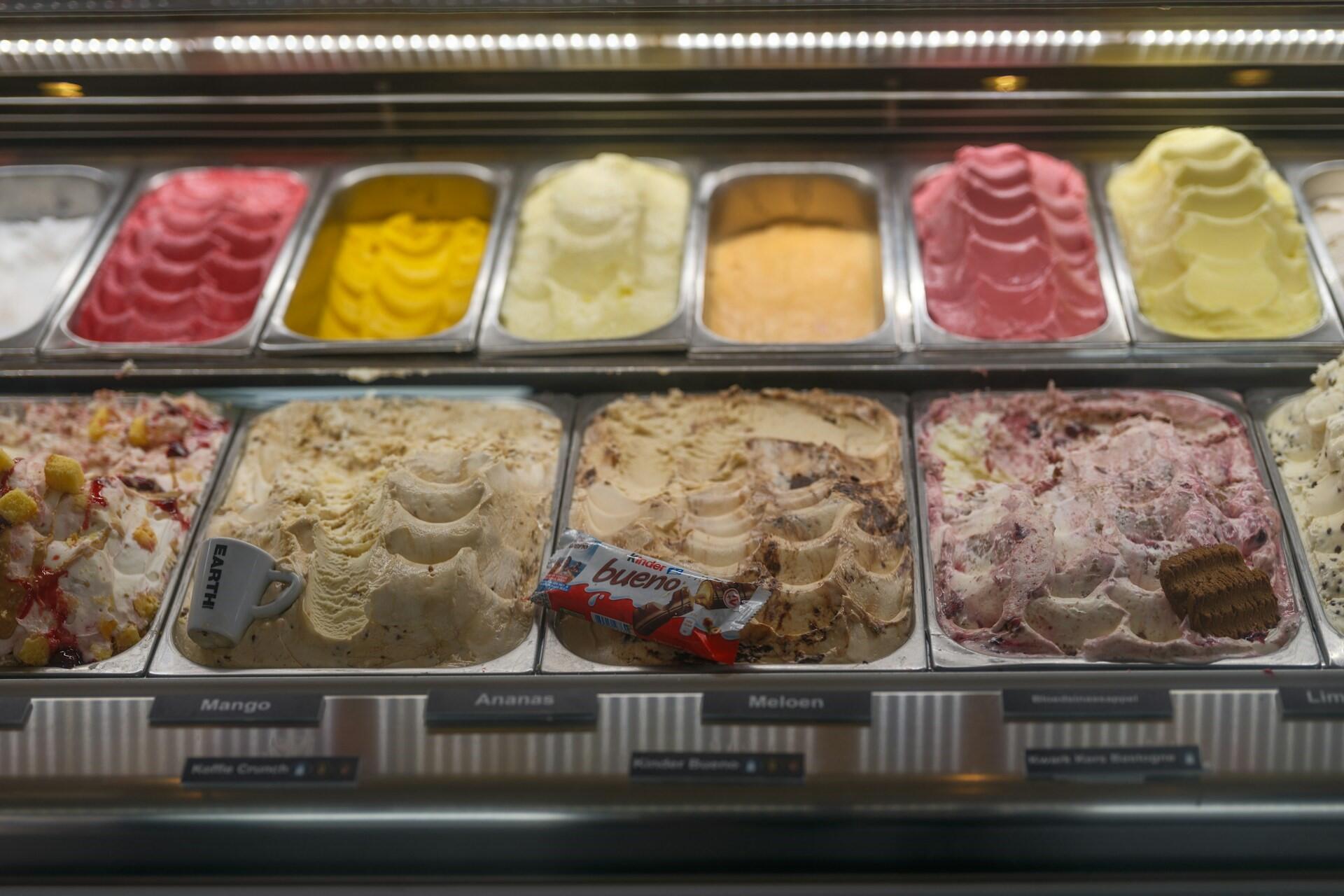 Rows of colourful ice cream tubs in a display case at a shop