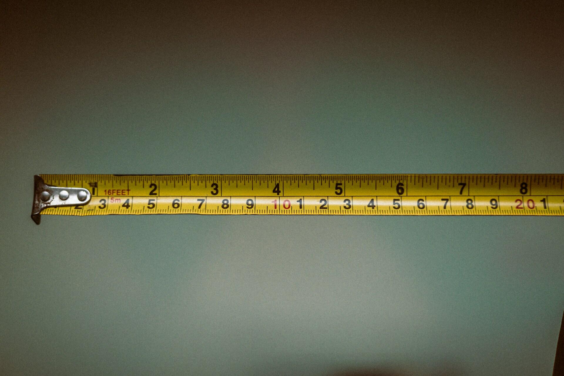 Yellow tape measure stretched horizontally showing measurement markings