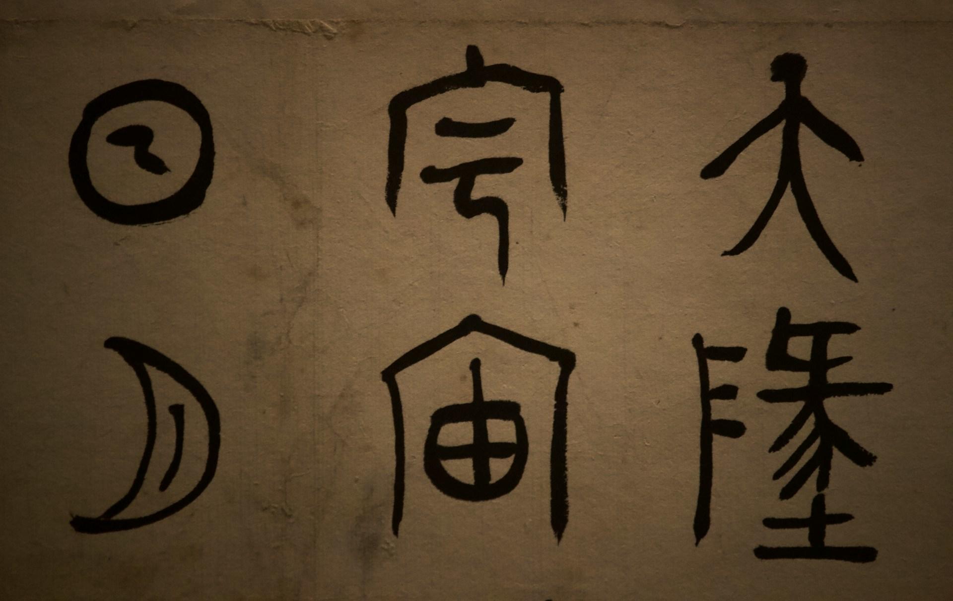 A set of six ancient Chinese characters painted in black on a brown background.