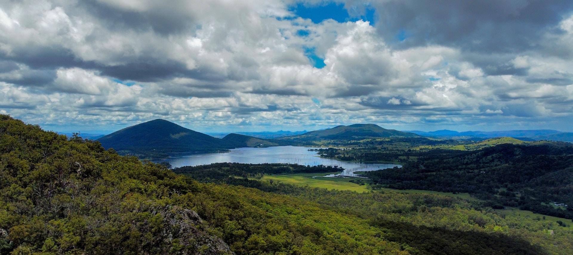 A panoramic shot of Lake Moogerah and its surrounding hillocks under cloudy skies.
