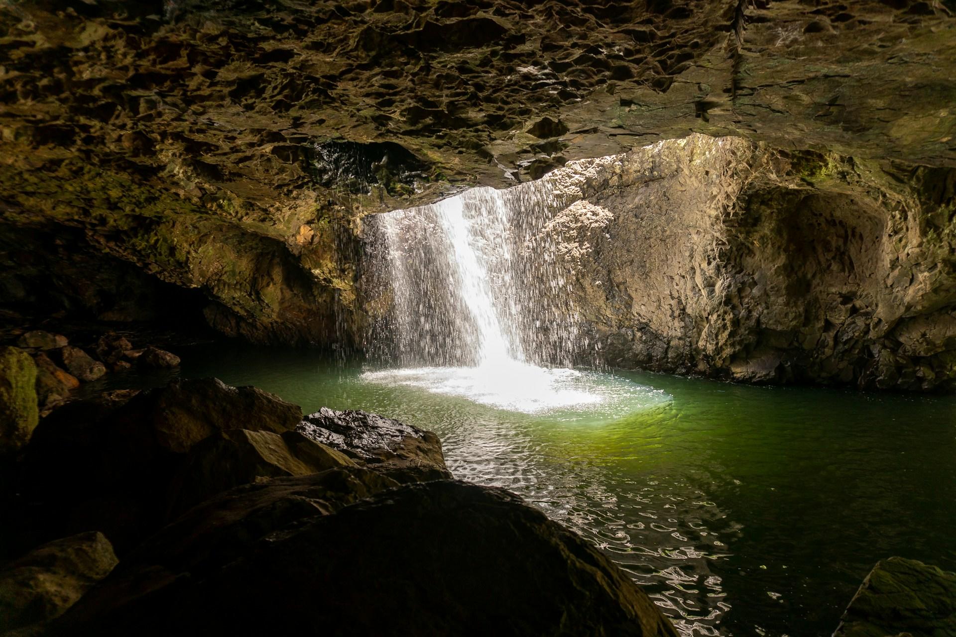 The Natural Bridge, in Springbrook National Park, with water cascading into a green pool through its oculus.