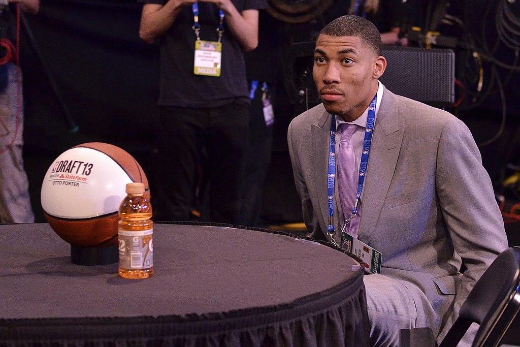 Otto Porter Jr, a former NBA player, sitting at a dressed-up table in the NBA Draft green room. He has a green room pass on a lanyard and a custom basketball with his name on it.