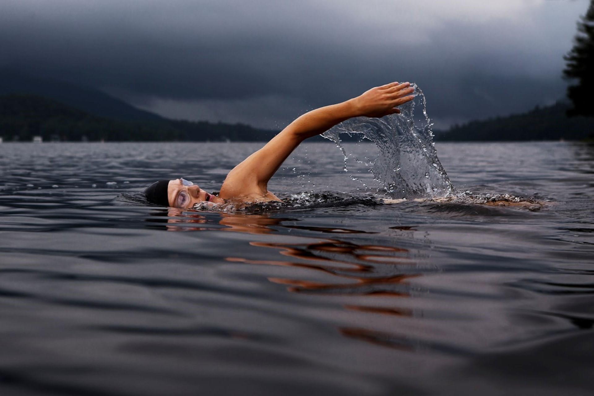 A person open water swimming in overcast weather.