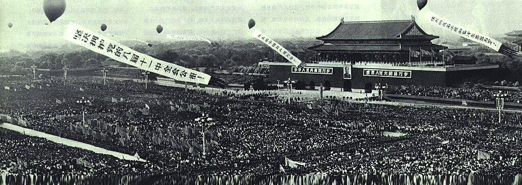 Black and white historic photo of a massive crowd at Tiananmen Square, with balloons and banners over the grand monument.