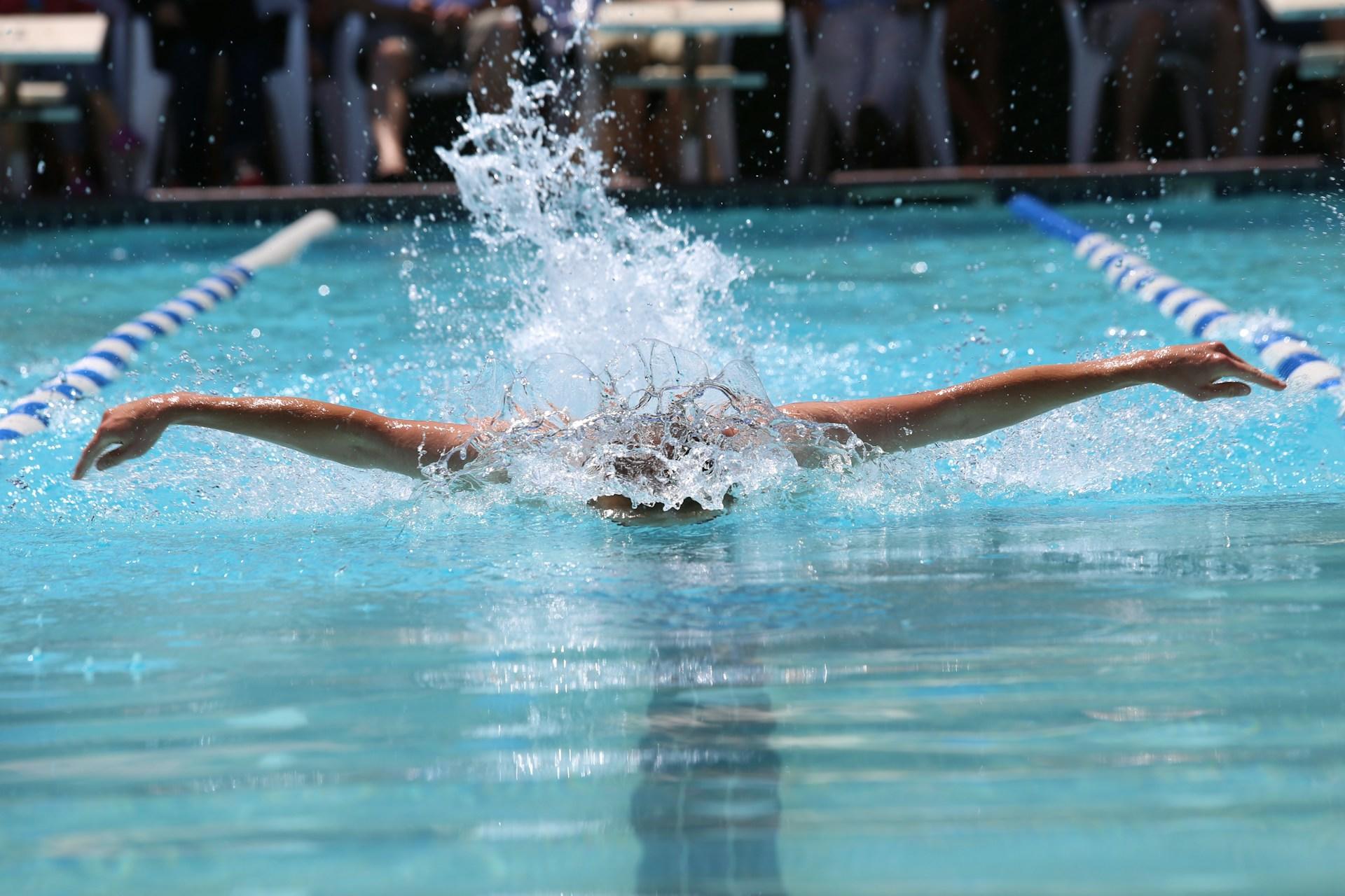 A competitive swimmer in the middle of a butterfly stroke.