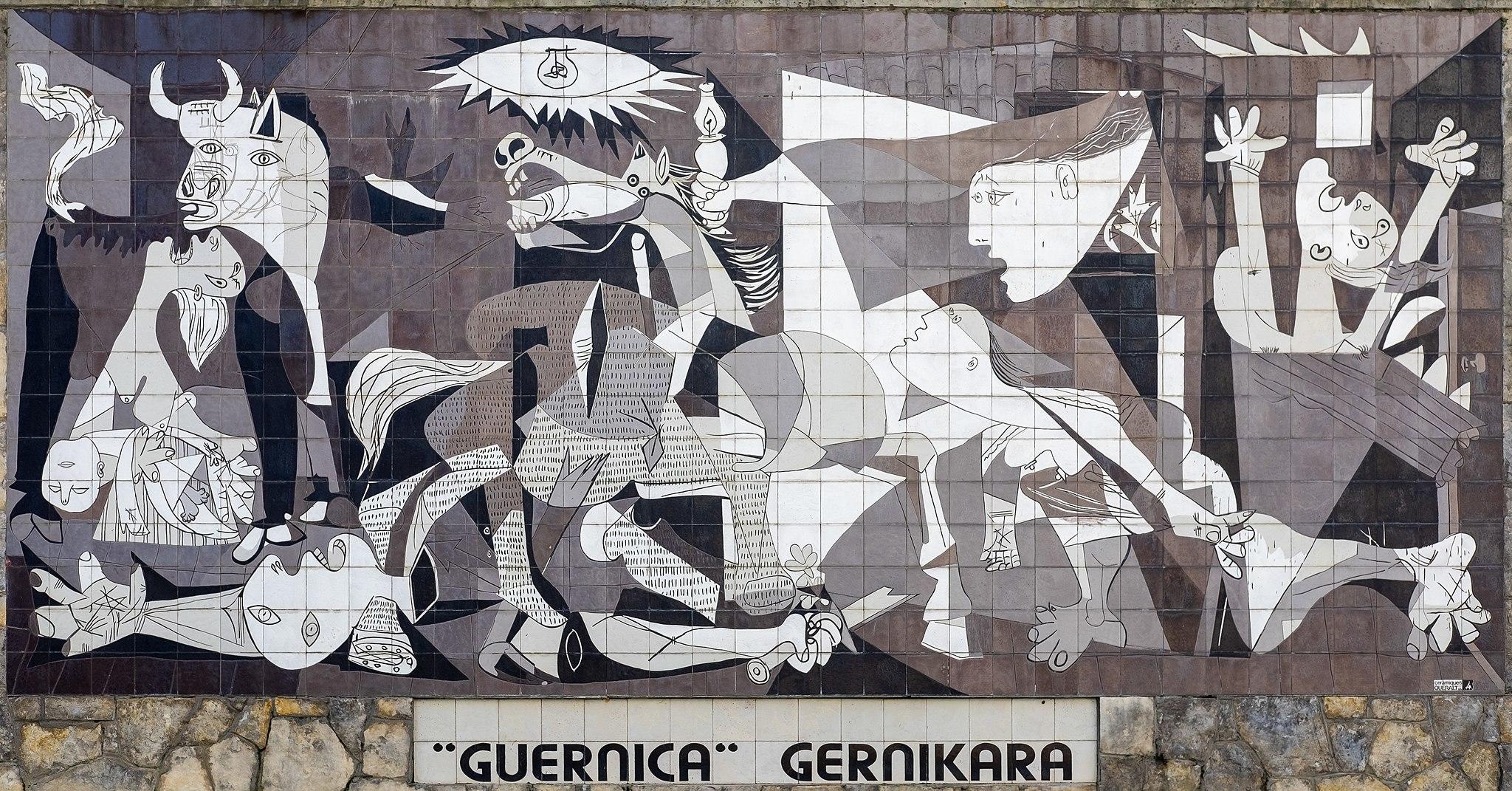 Large black and white mural depicting Pablo Picasso's "Guernica" with various abstract figures representing suffering and chaos, displayed on a wall with the words "GUERNICA" and "GERNIKARA" below it.