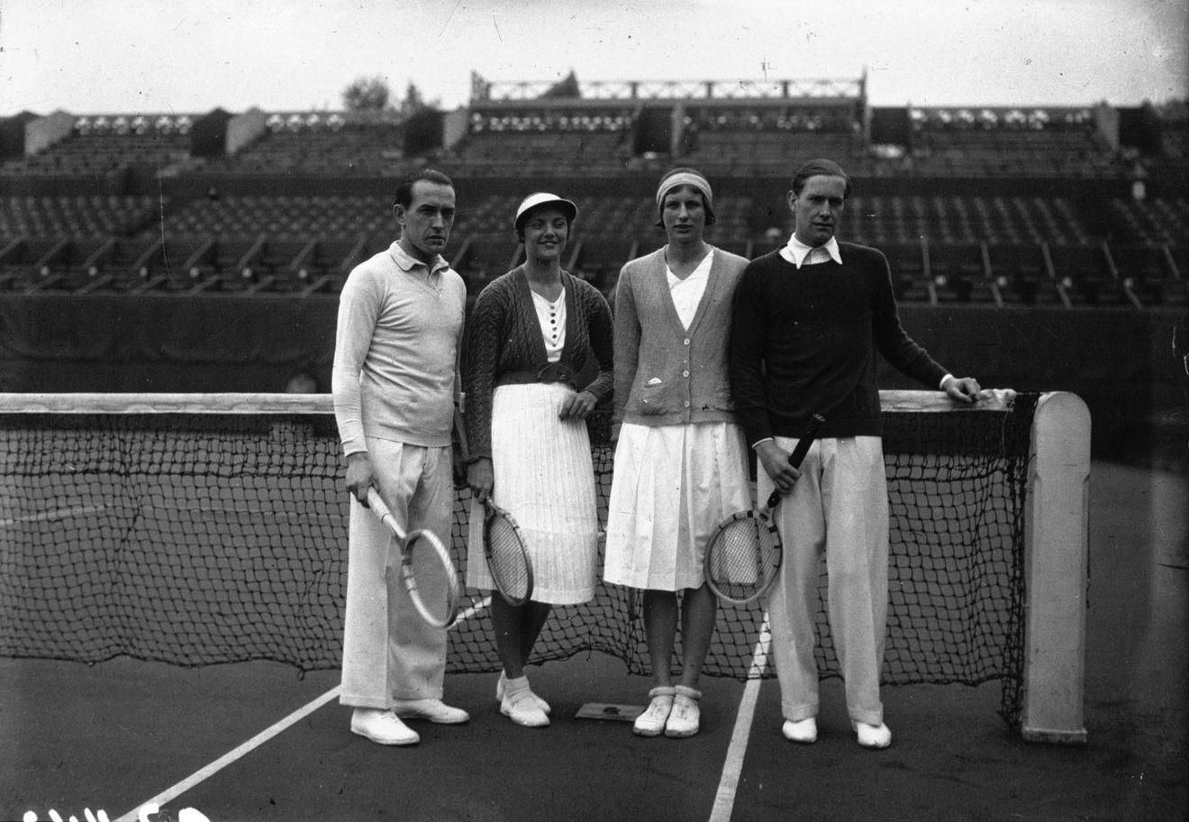 A greyscale group photo posing against the net on a tennis court.