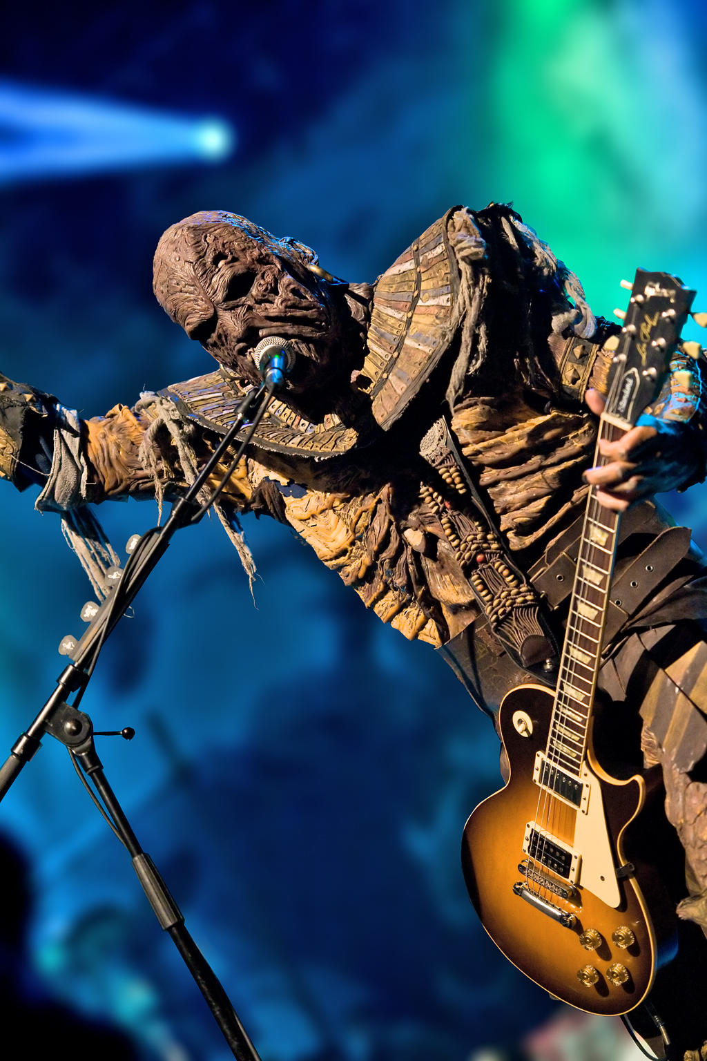 A man in A man in a monster costume playing guitar and singing on stage.