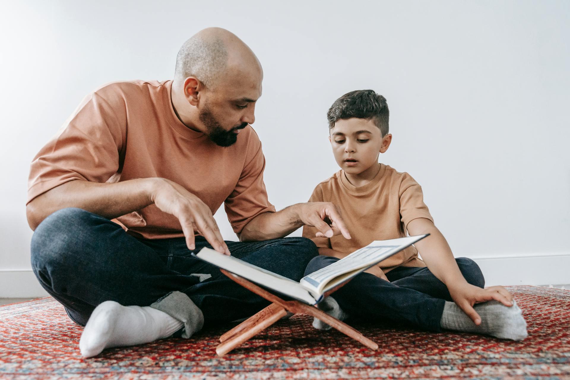 An adult man teaching a young boy to read with a book