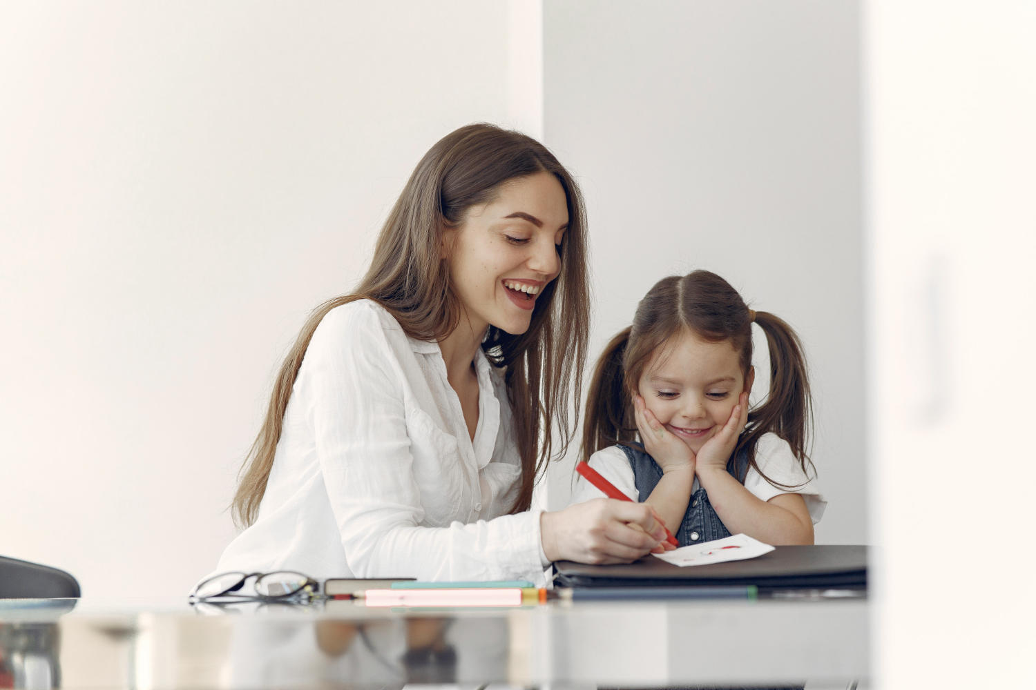An adult female tutor and a young girl learner working on schoolwork together