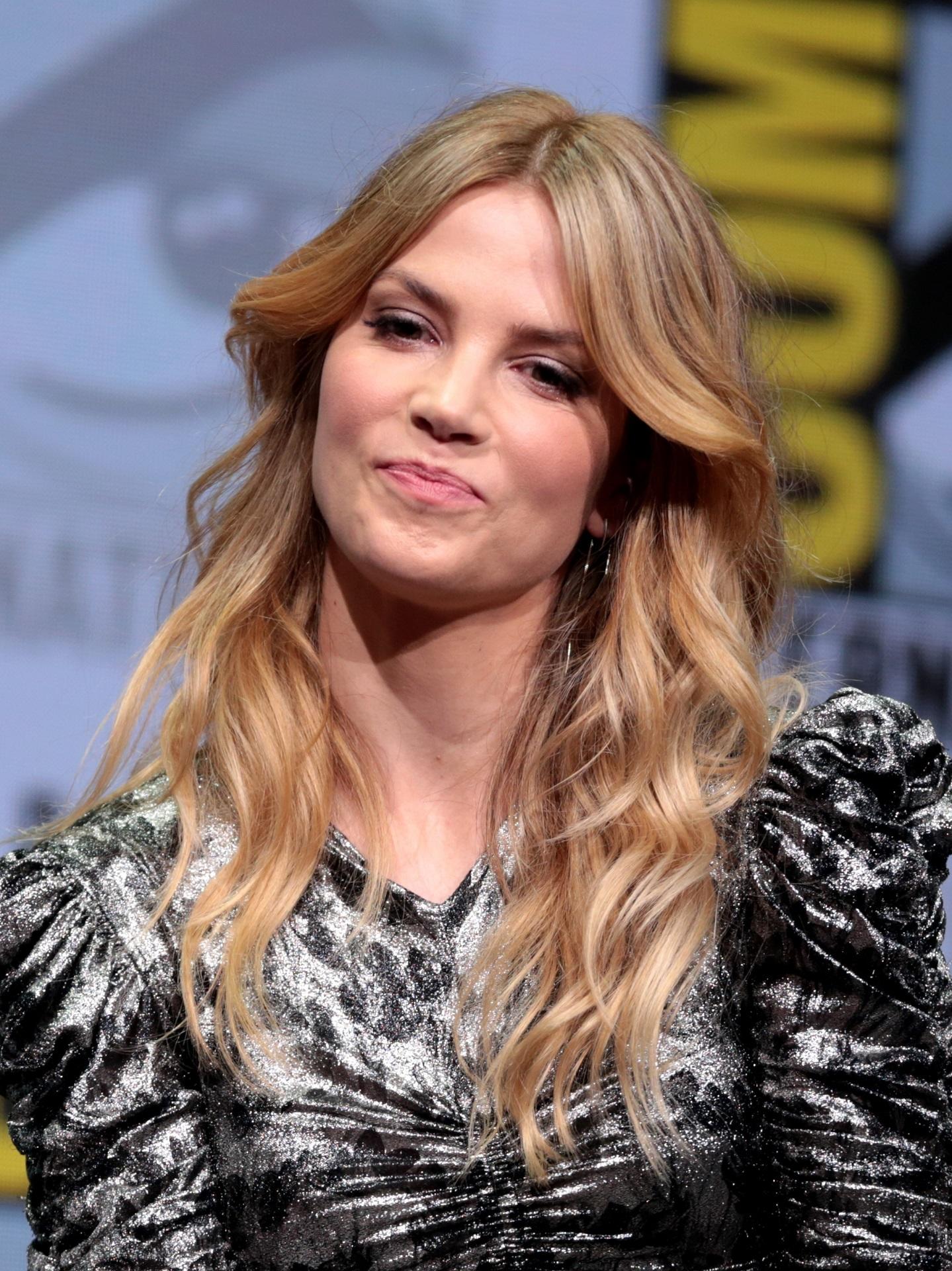 A woman with long blond hair, wearing a patterned dress. 