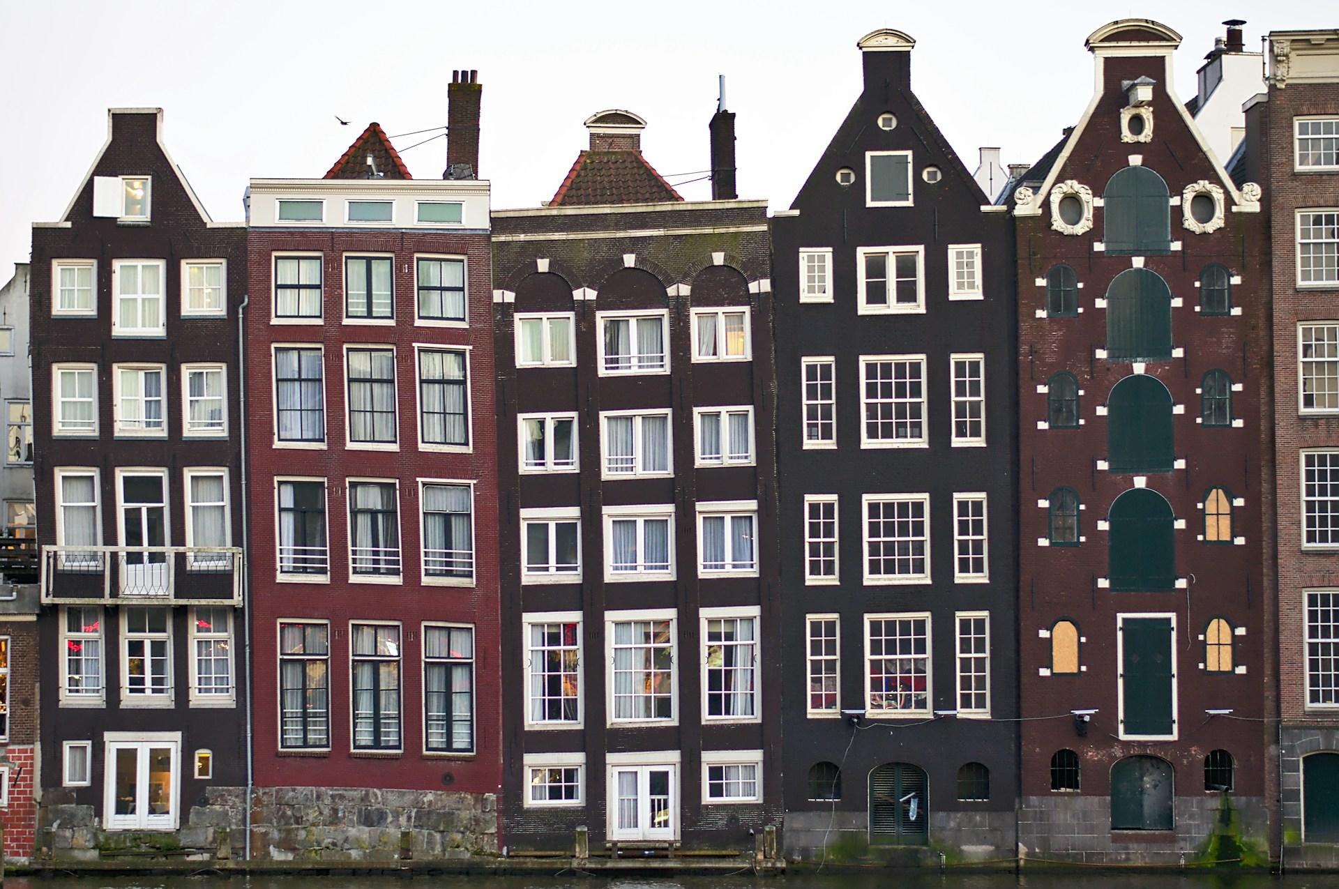a row of narrow apartment fronts overlooking a waterway.