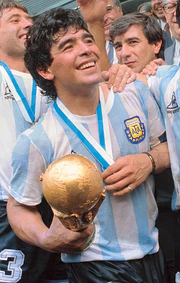A person wearing a blue-and-white striped jersey smiles and holds a golden trophy.