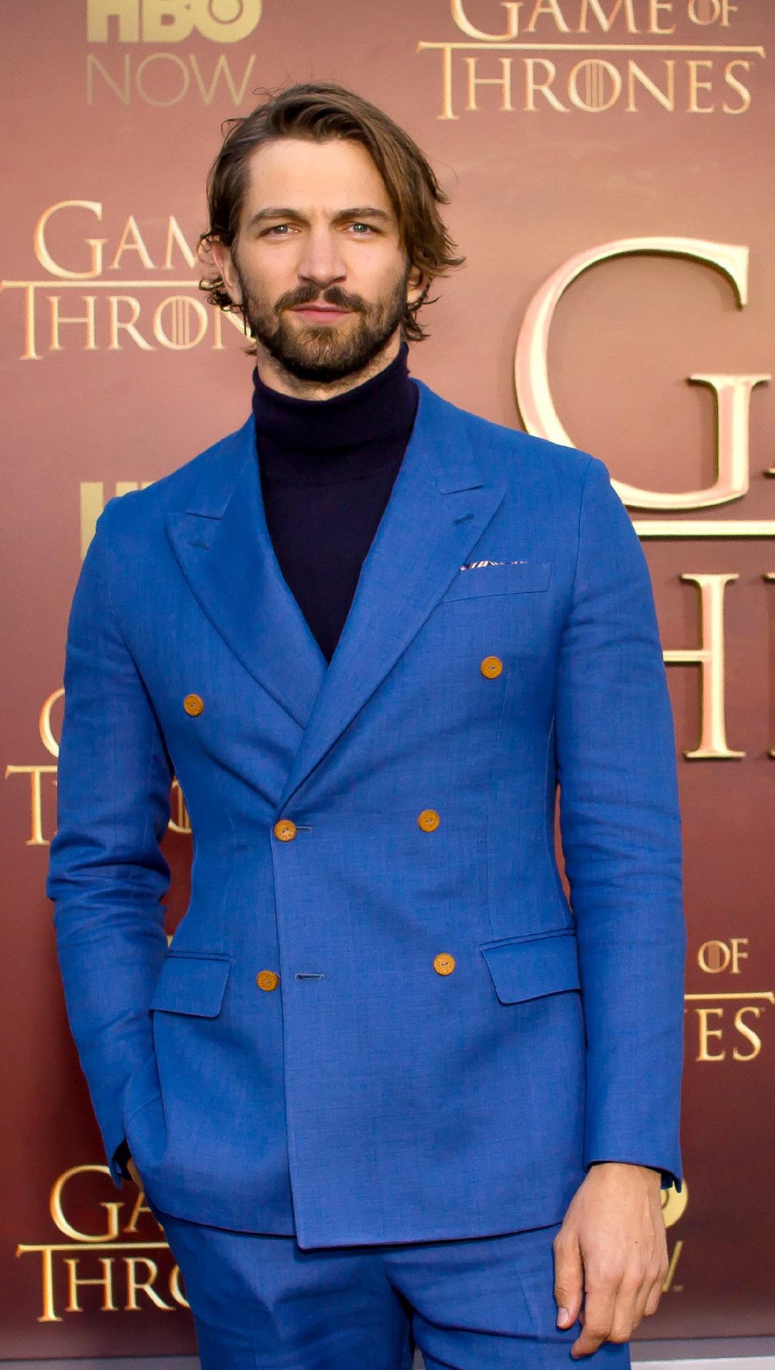 A man wearing a blue suit with a black turtleneck shirt. 