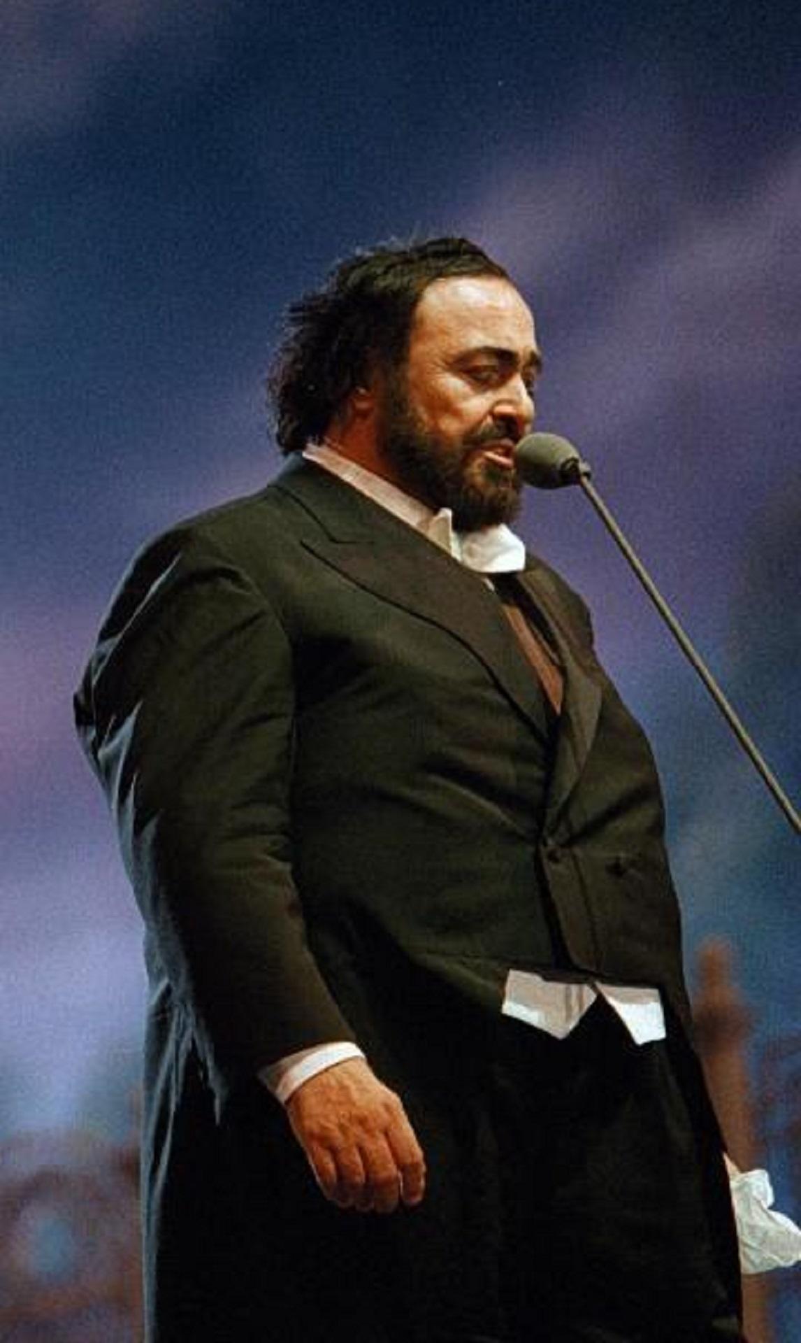 A man in a tuxedo stands before a microphone.