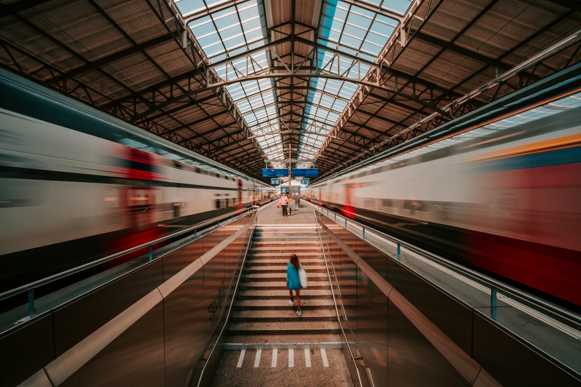 Red and white trains inside a Train Station.