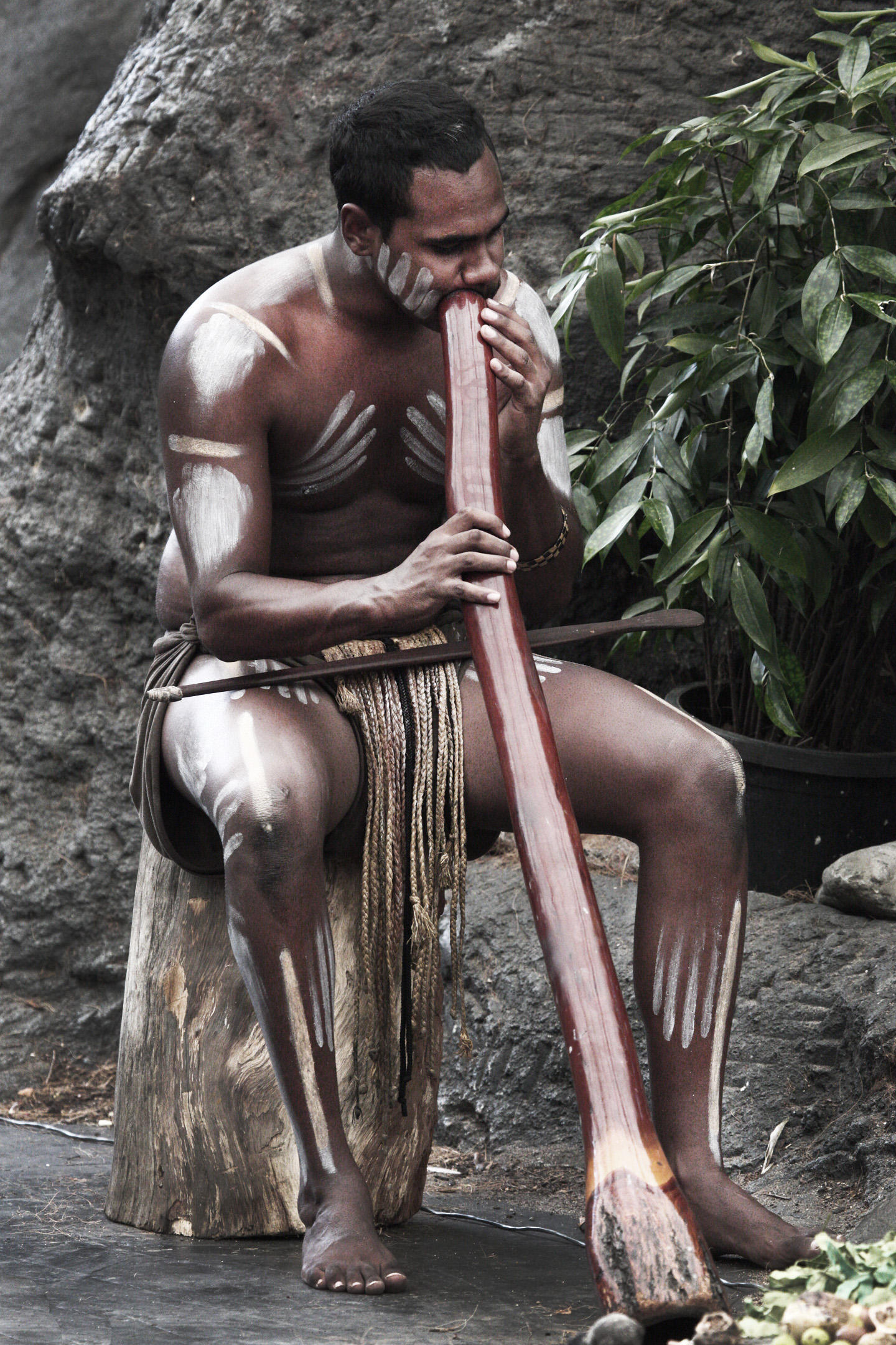 A man sits and play the didgeridoo.