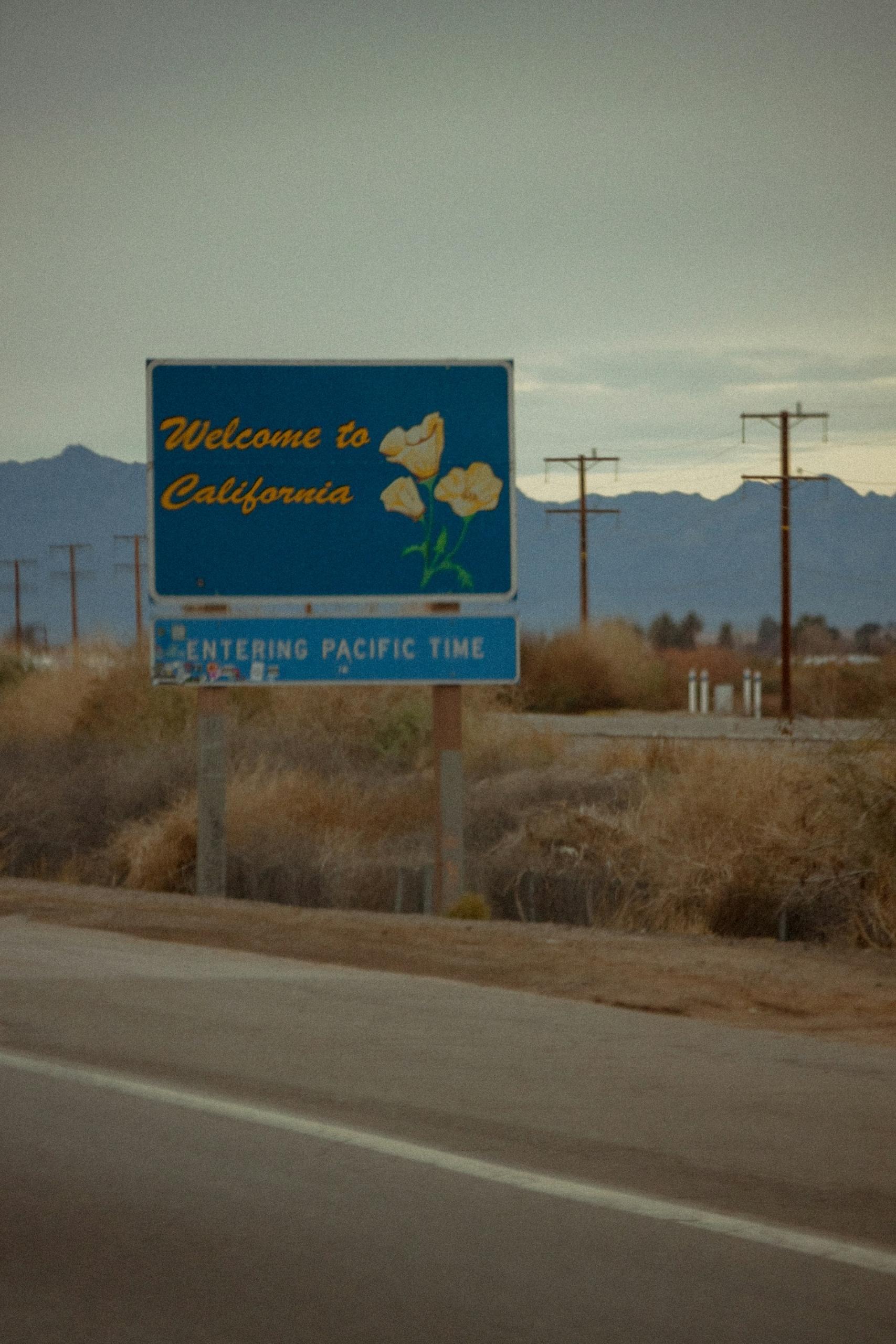A blue road sign with gold lettering on it on a hazy day. 