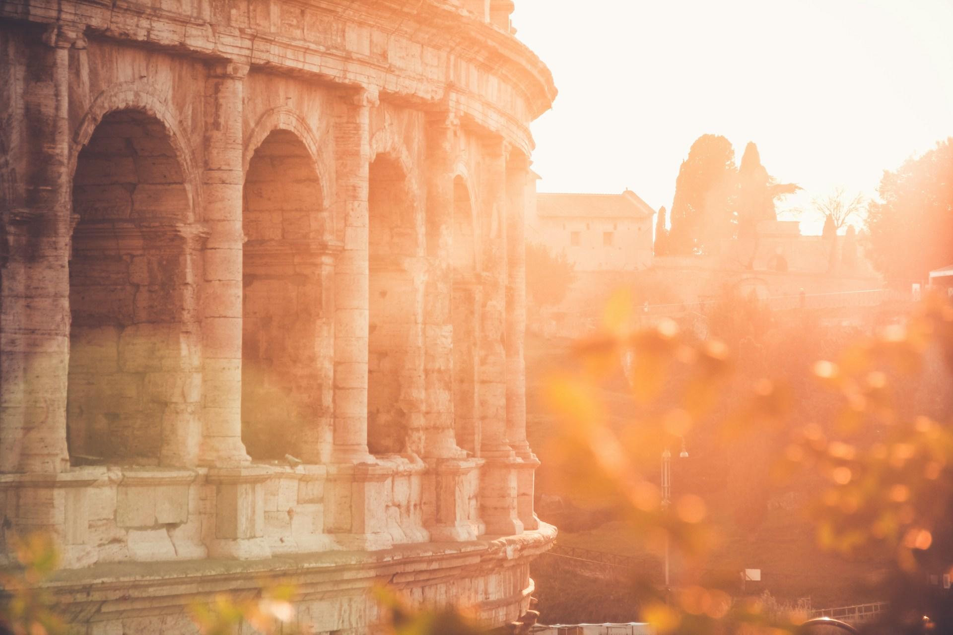 The sun setting by the colosseum in Rome, Italy.