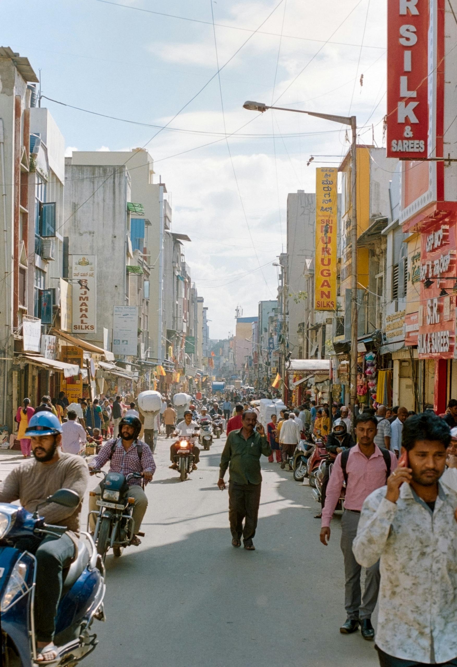 A street with all buildings and signs attached to them, and people walking. 