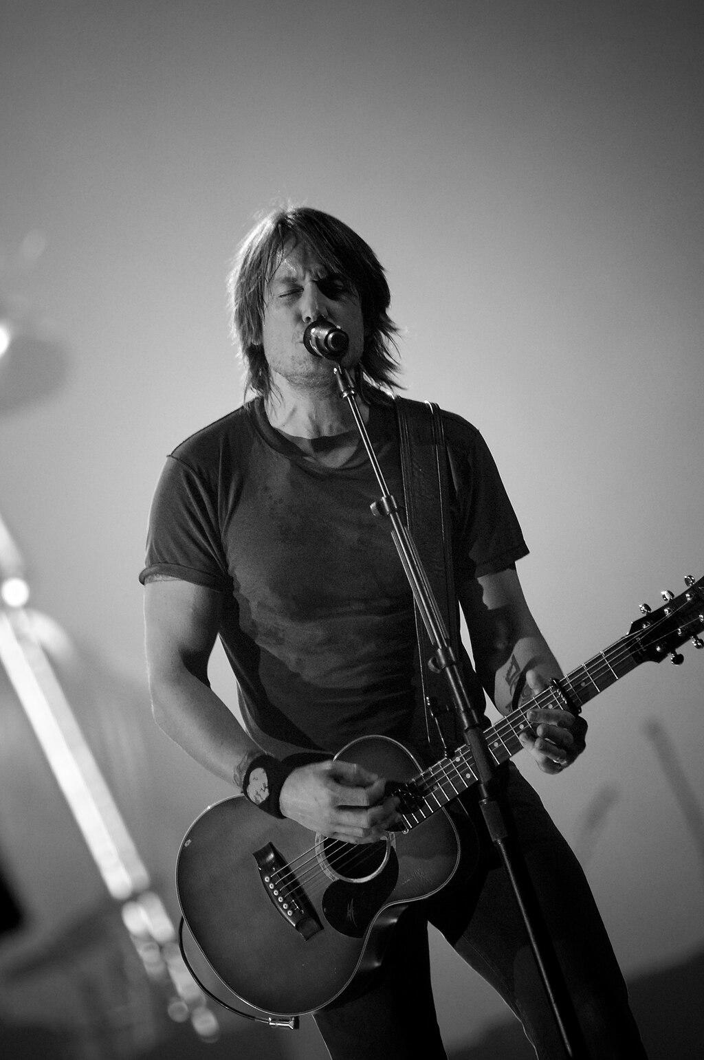 Keith Urban singing on stage with a guitar