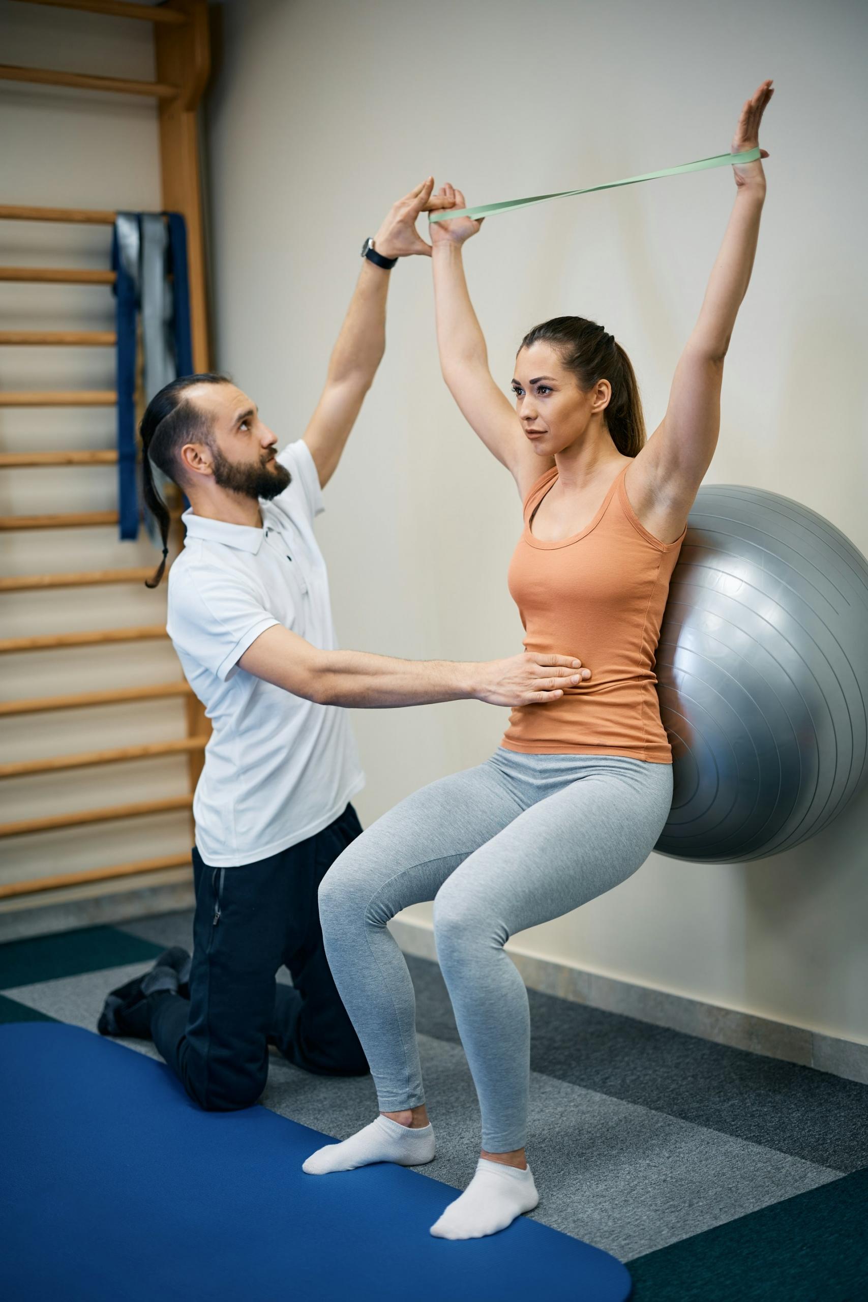 A person does exercises with another guiding them.