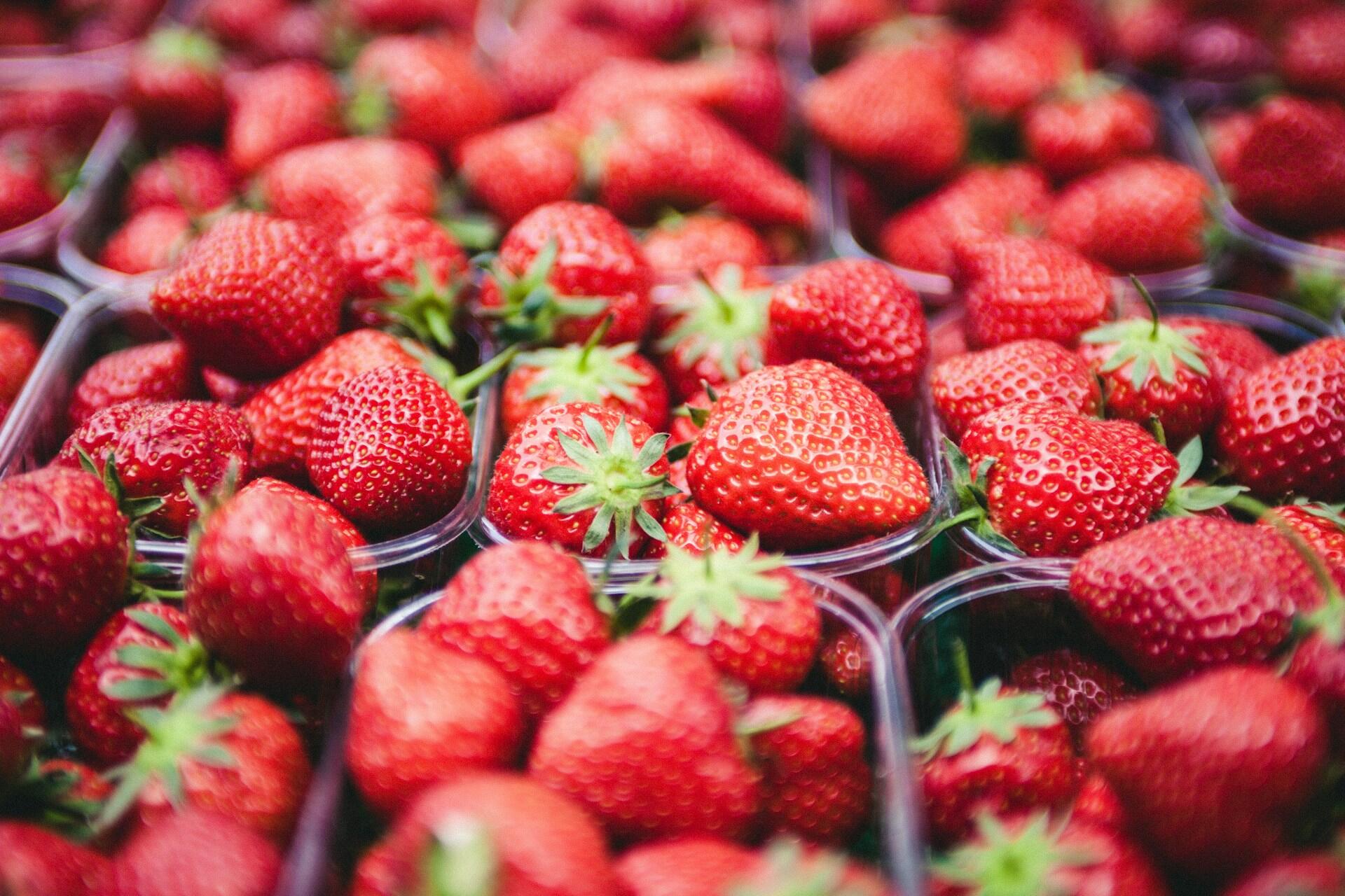 Fresh strawberries in plastic punnets arranged closely together.