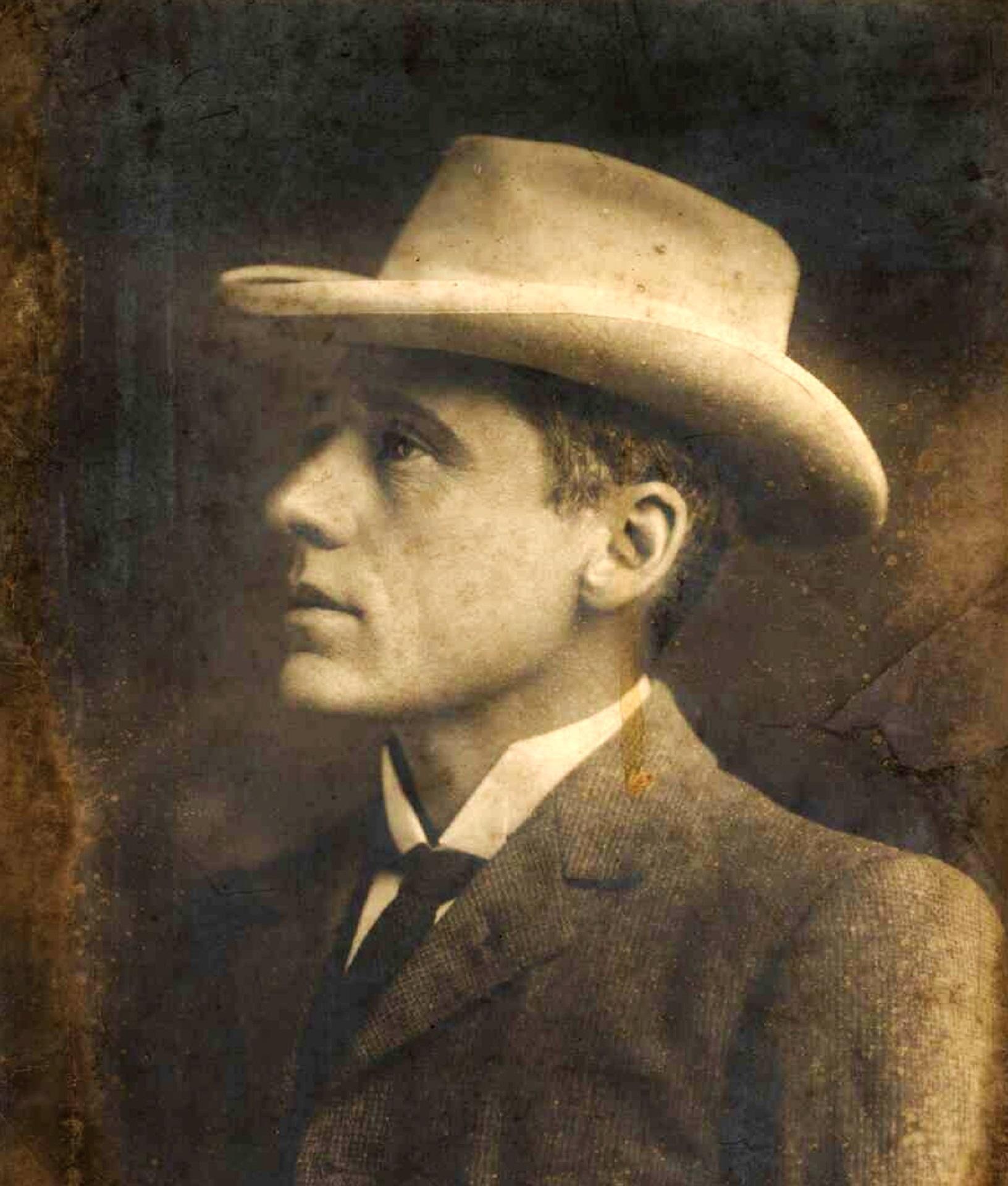A sepia-toned portrait of a man wearing a cowboy hat and a suit.