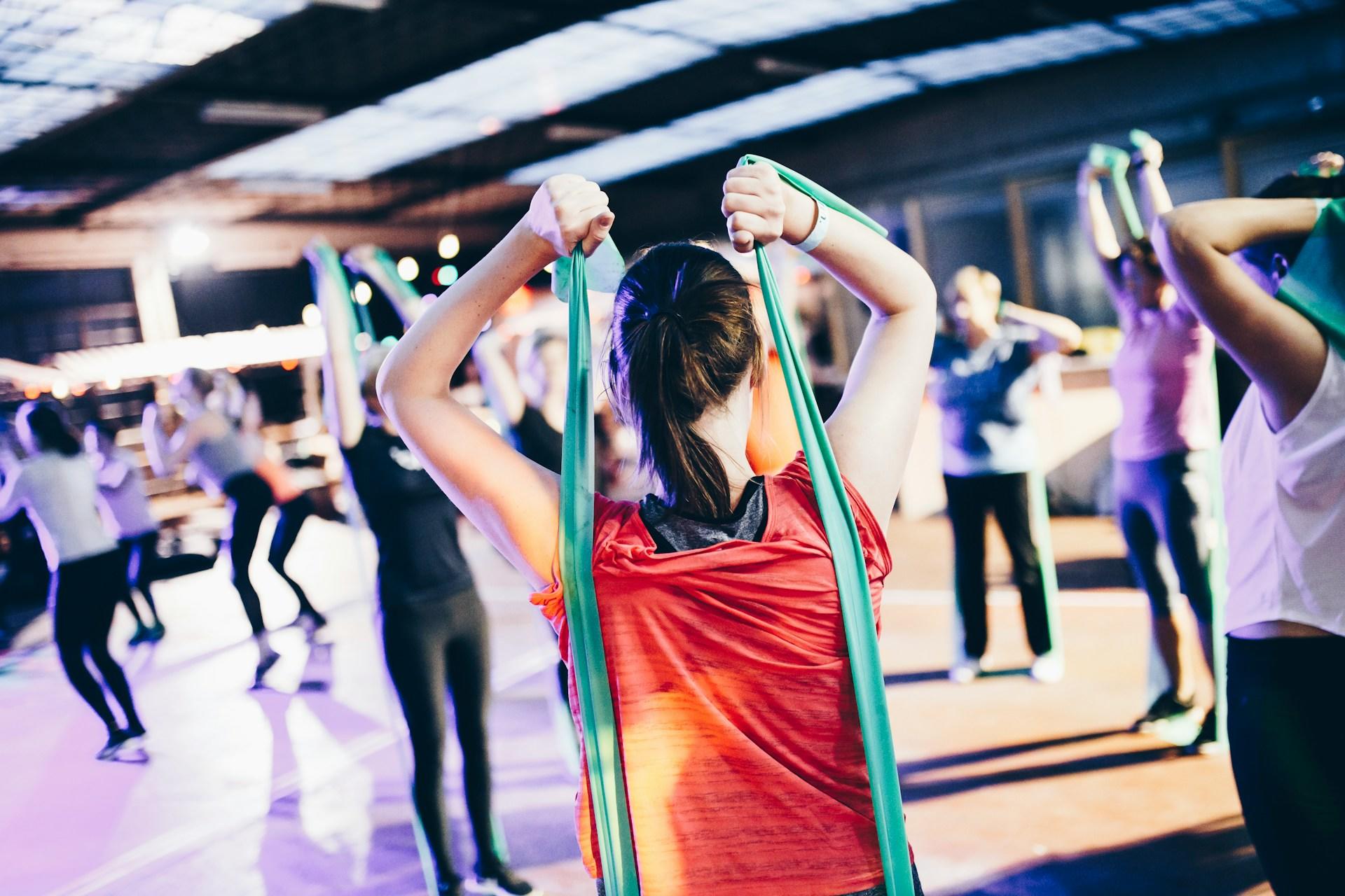 A group of people work out with resistance bands indoors.