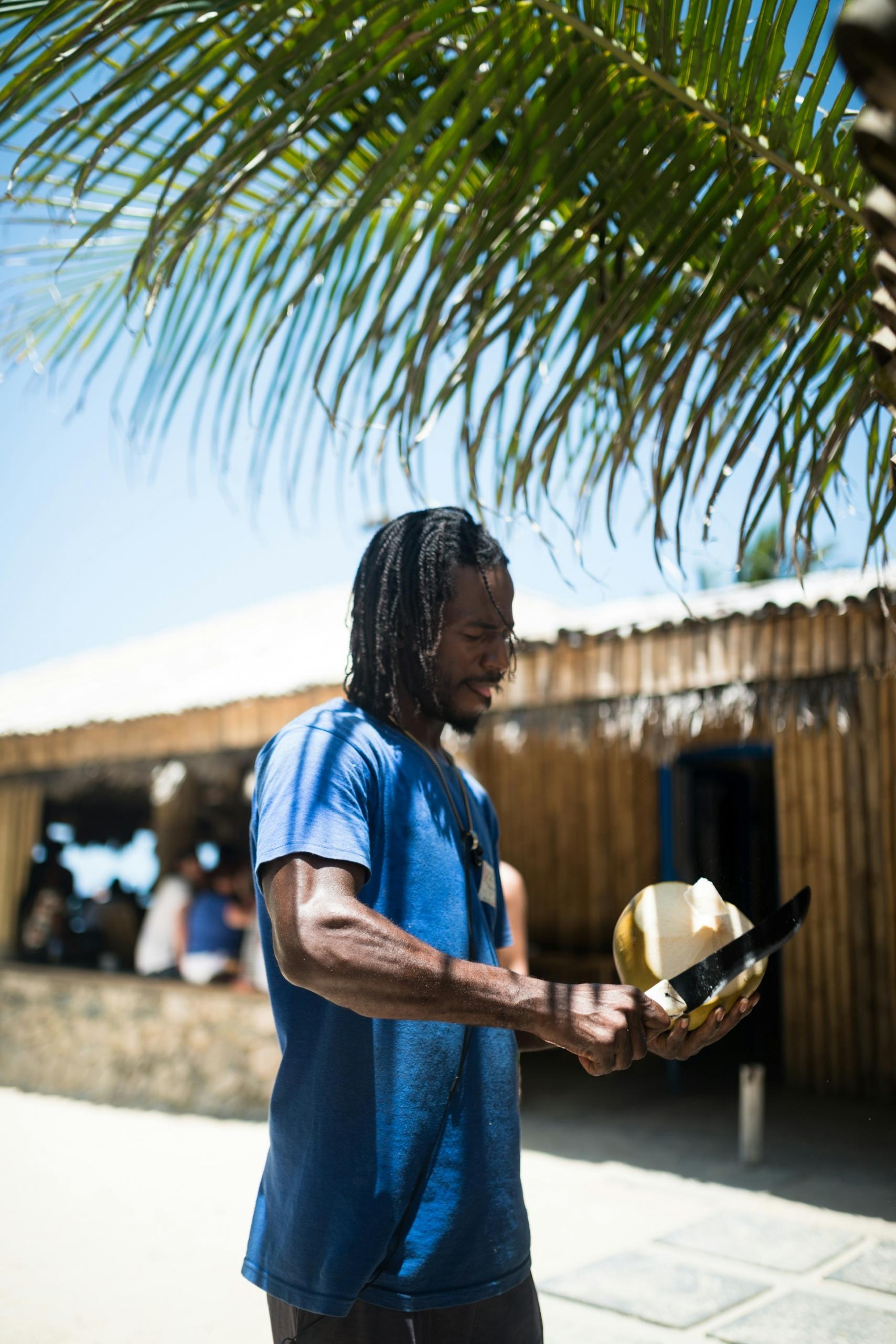 A man holding a knife cutting a coconut.