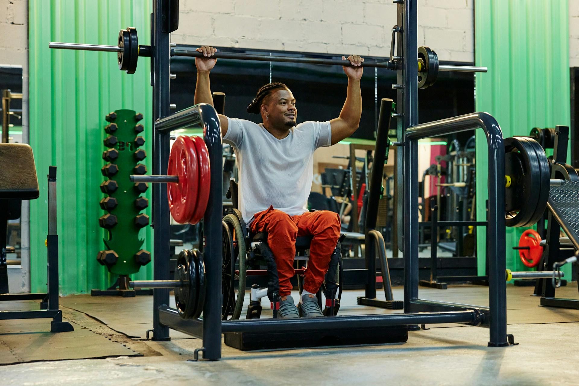 A Person wearing a white top and orange sweatpants sits in a workout machine.