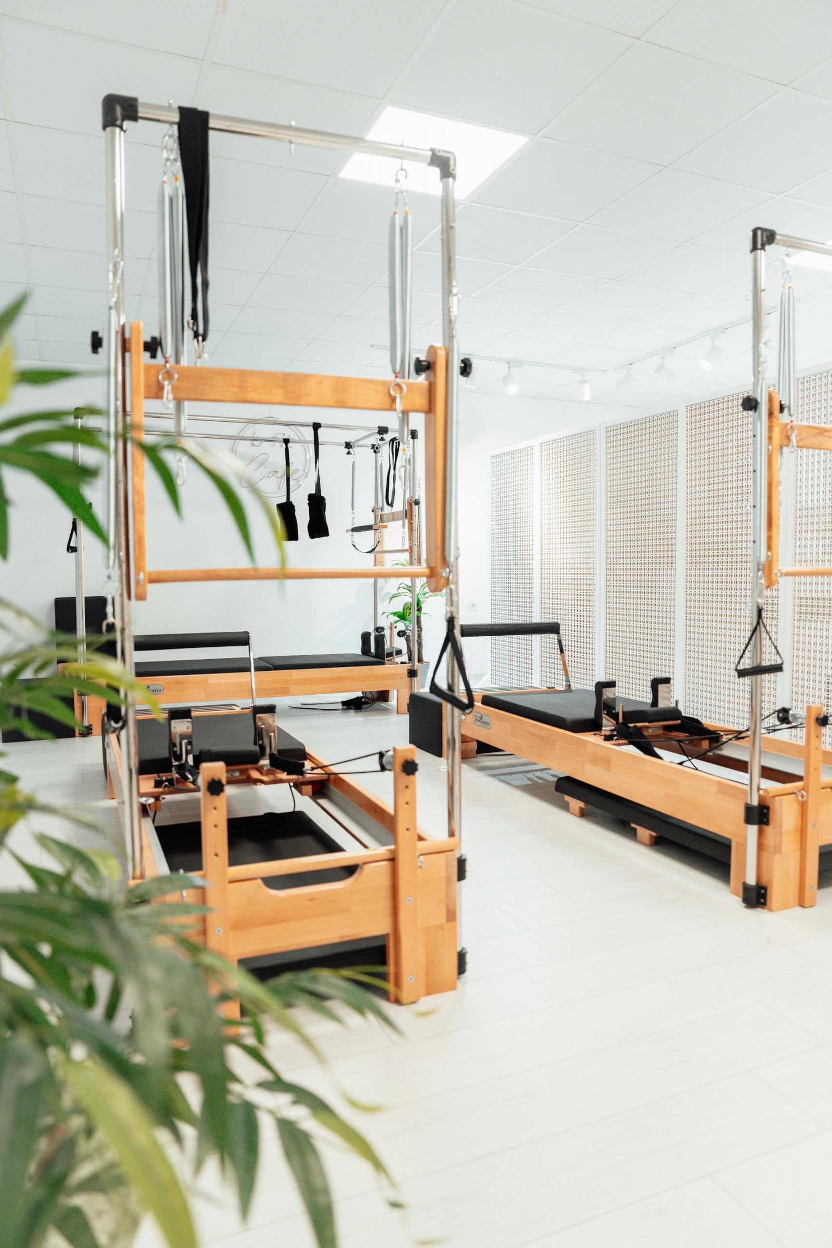 Two wooden Pilates tables in a brightly lit room. 