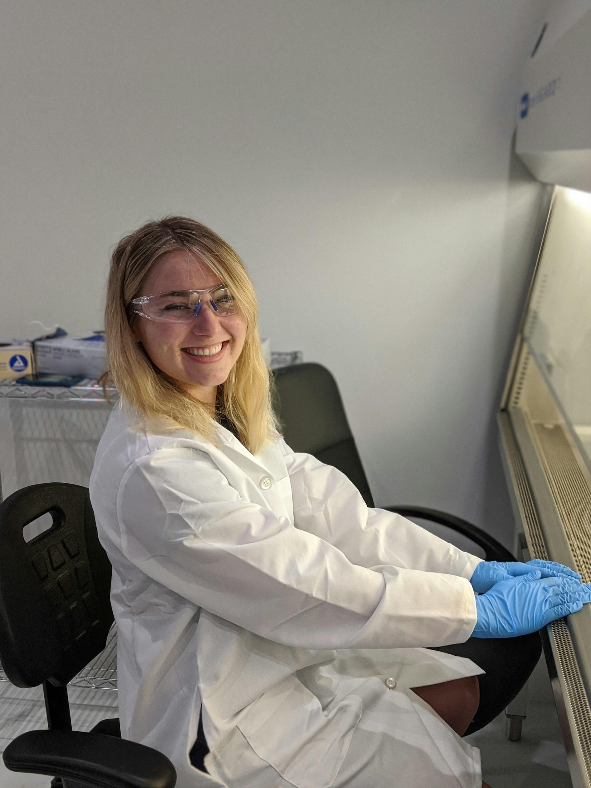 A person wearing a lab coat and safety goggles.